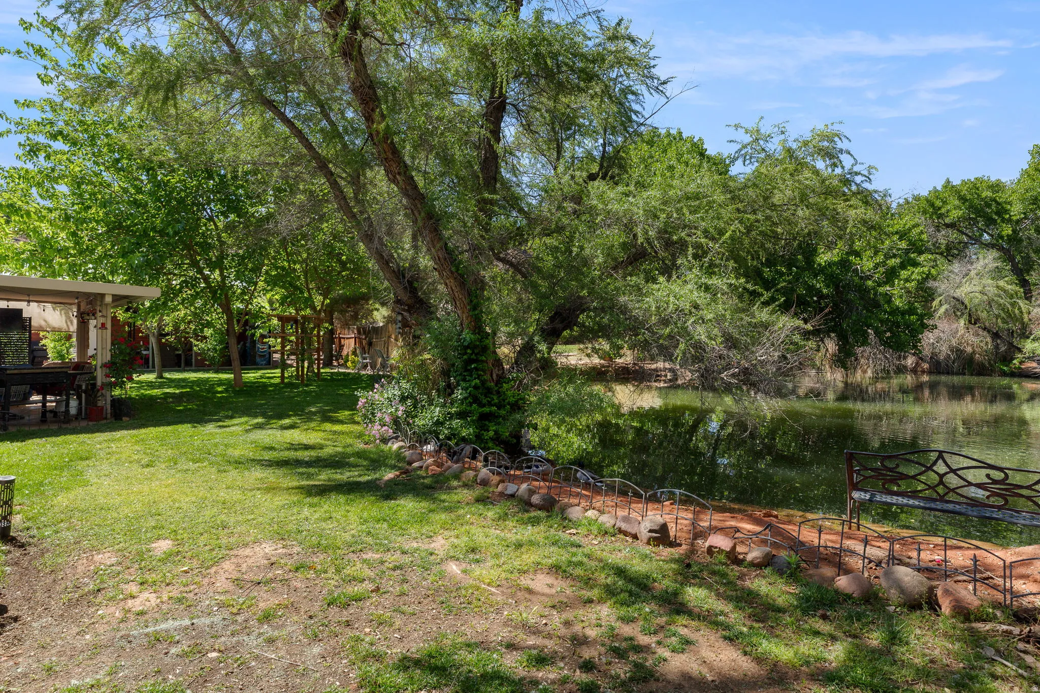 Expansive green lawn with mature trees and a tranquil pond feature