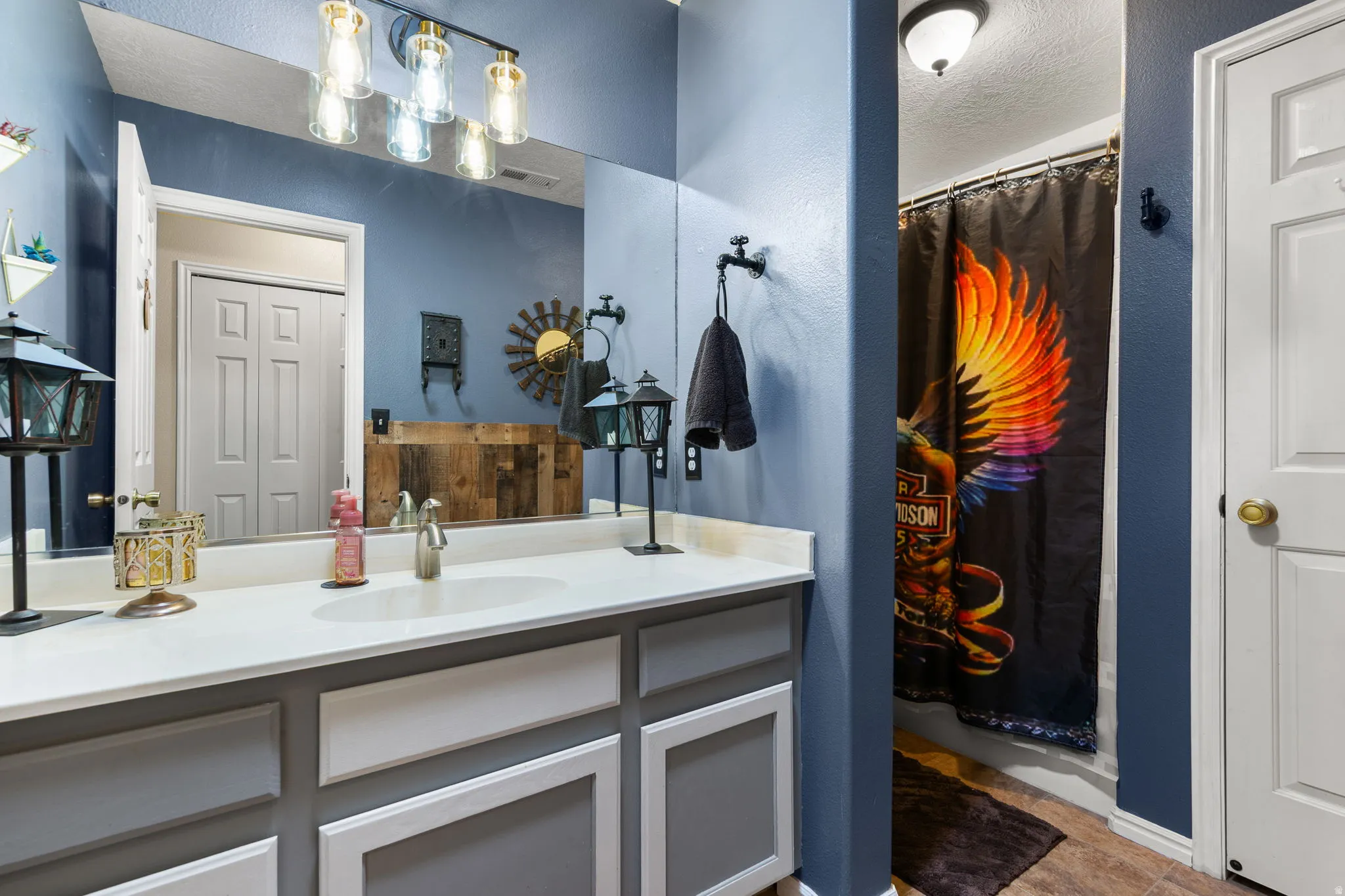 Bathroom vanity featuring a white countertop with integrated sink, two-tone cabinetry, and a full-width mirror