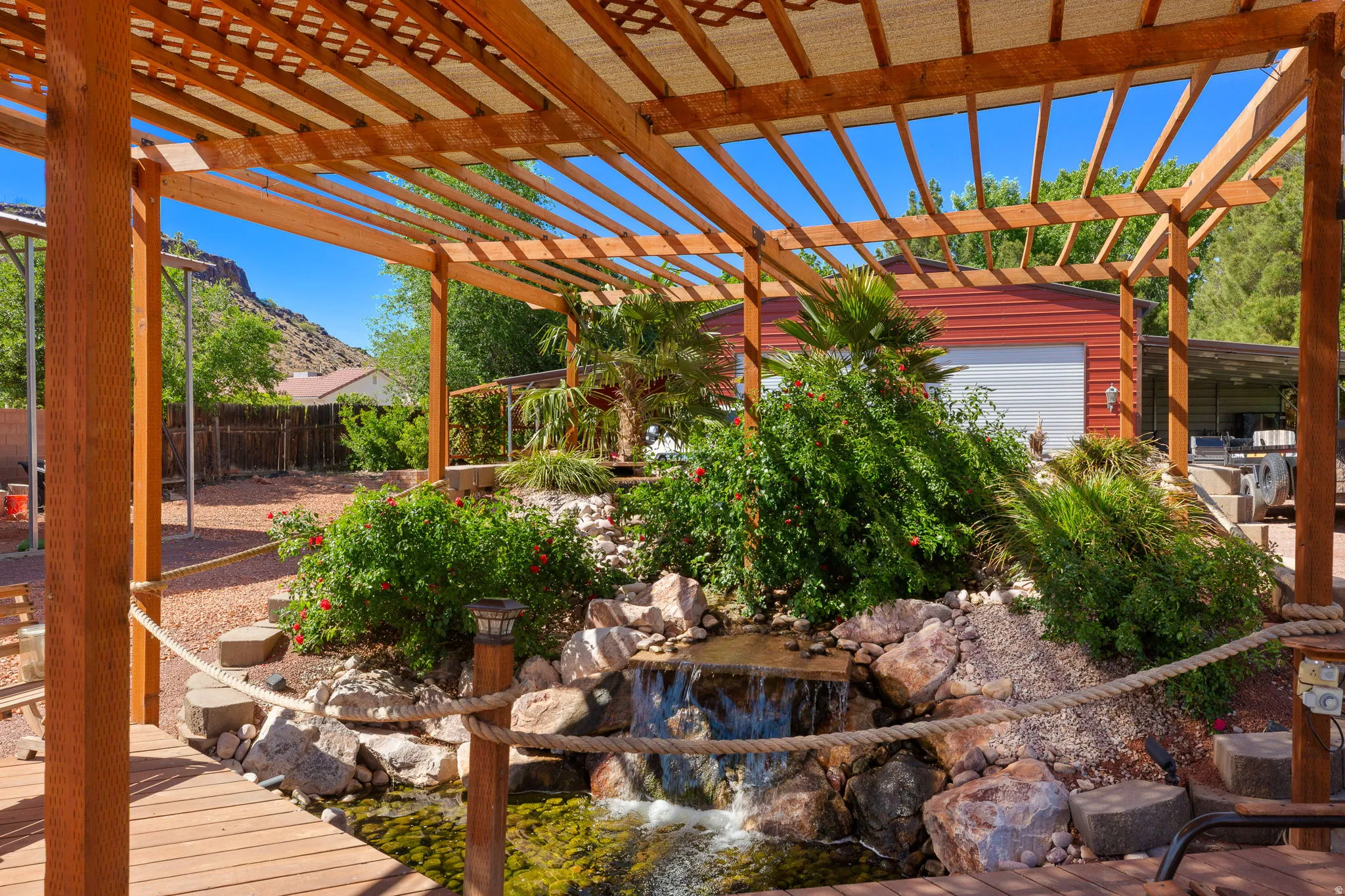 Outdoor living space featuring a wood pergola and a tranquil water feature with a waterfall