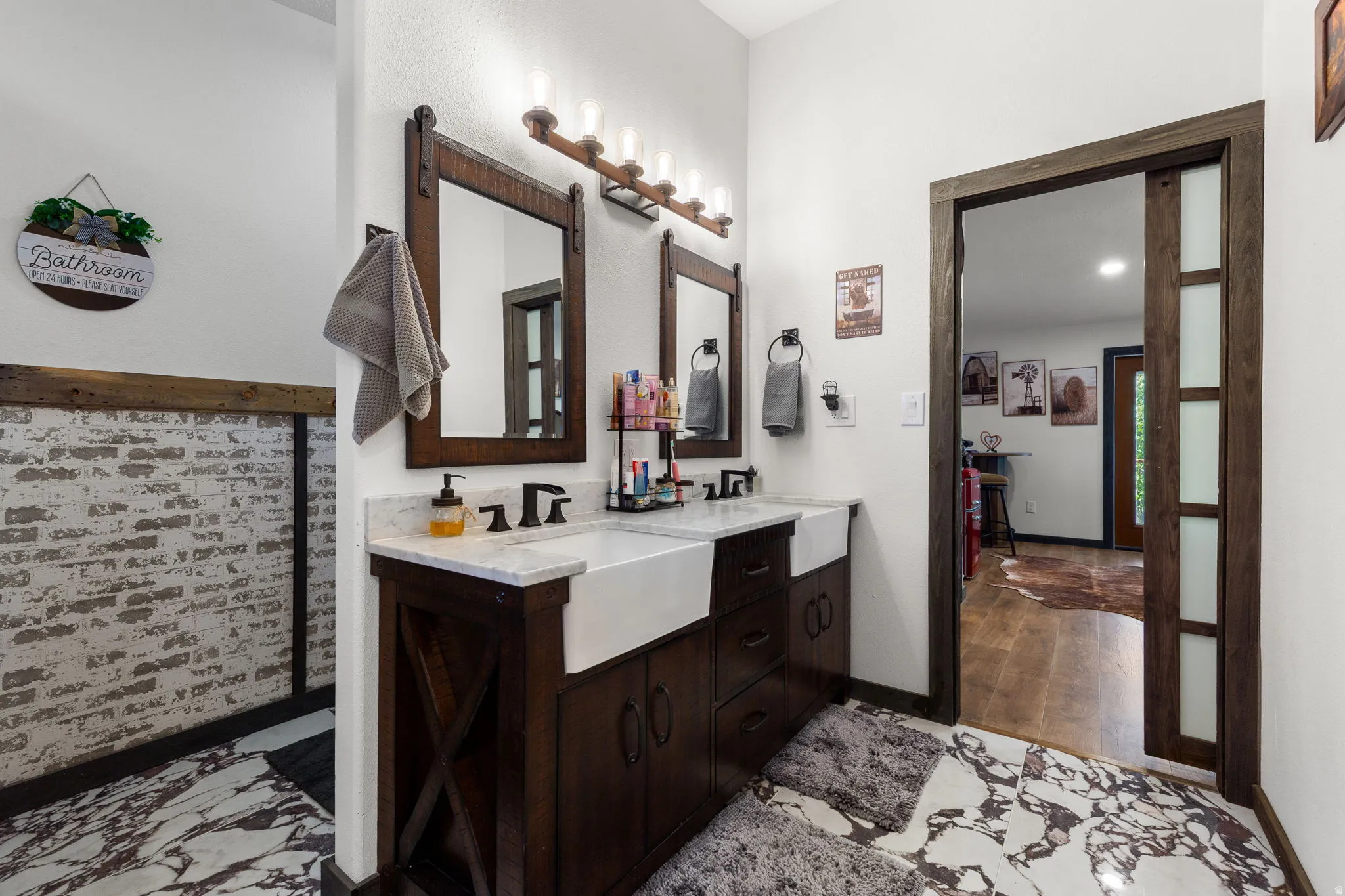 Double vanity with white farmhouse sinks, dark wood cabinetry, and a light-toned countertop