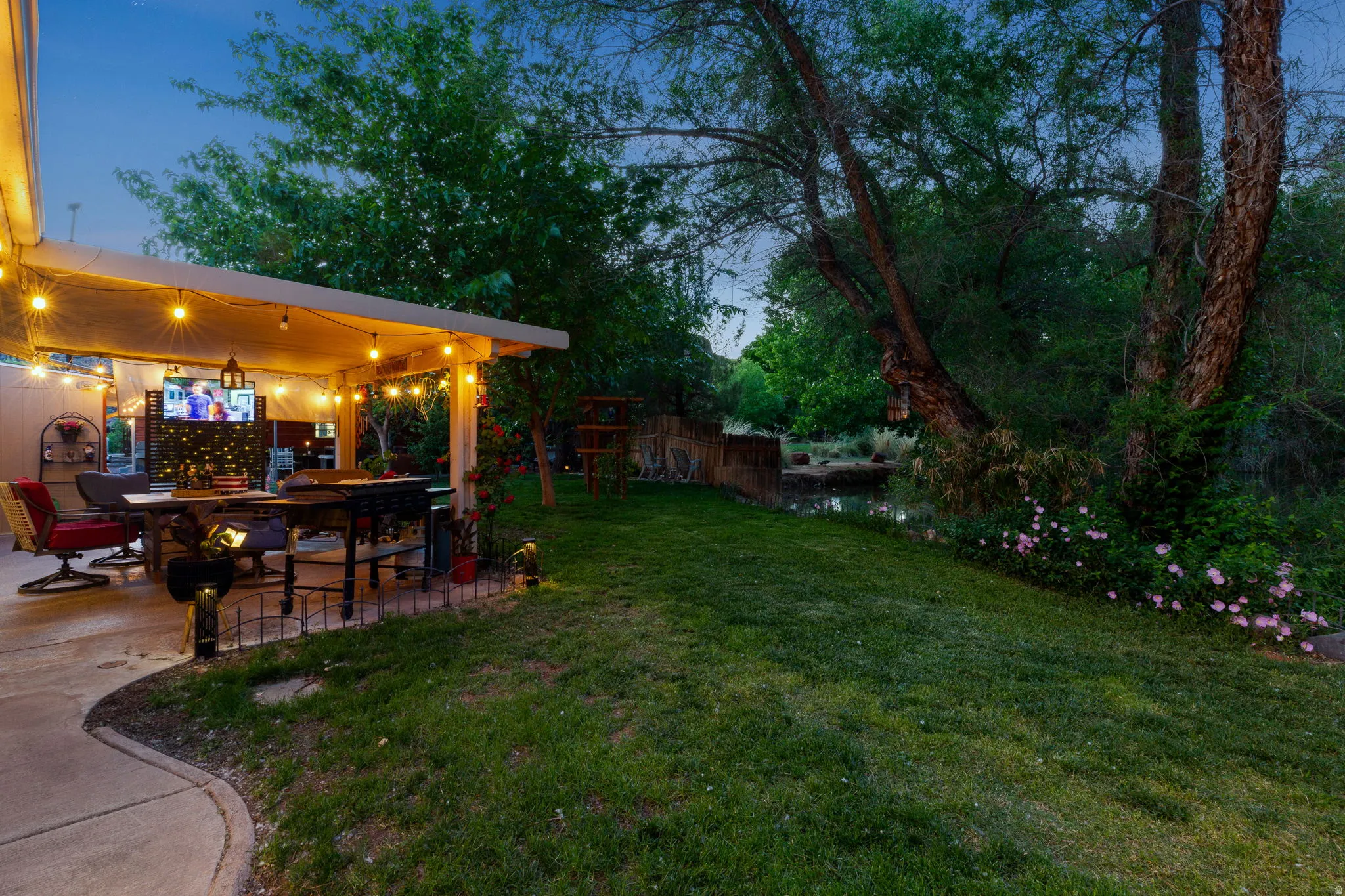 Expansive outdoor patio featuring an attached pergola with string lighting and a concrete surface