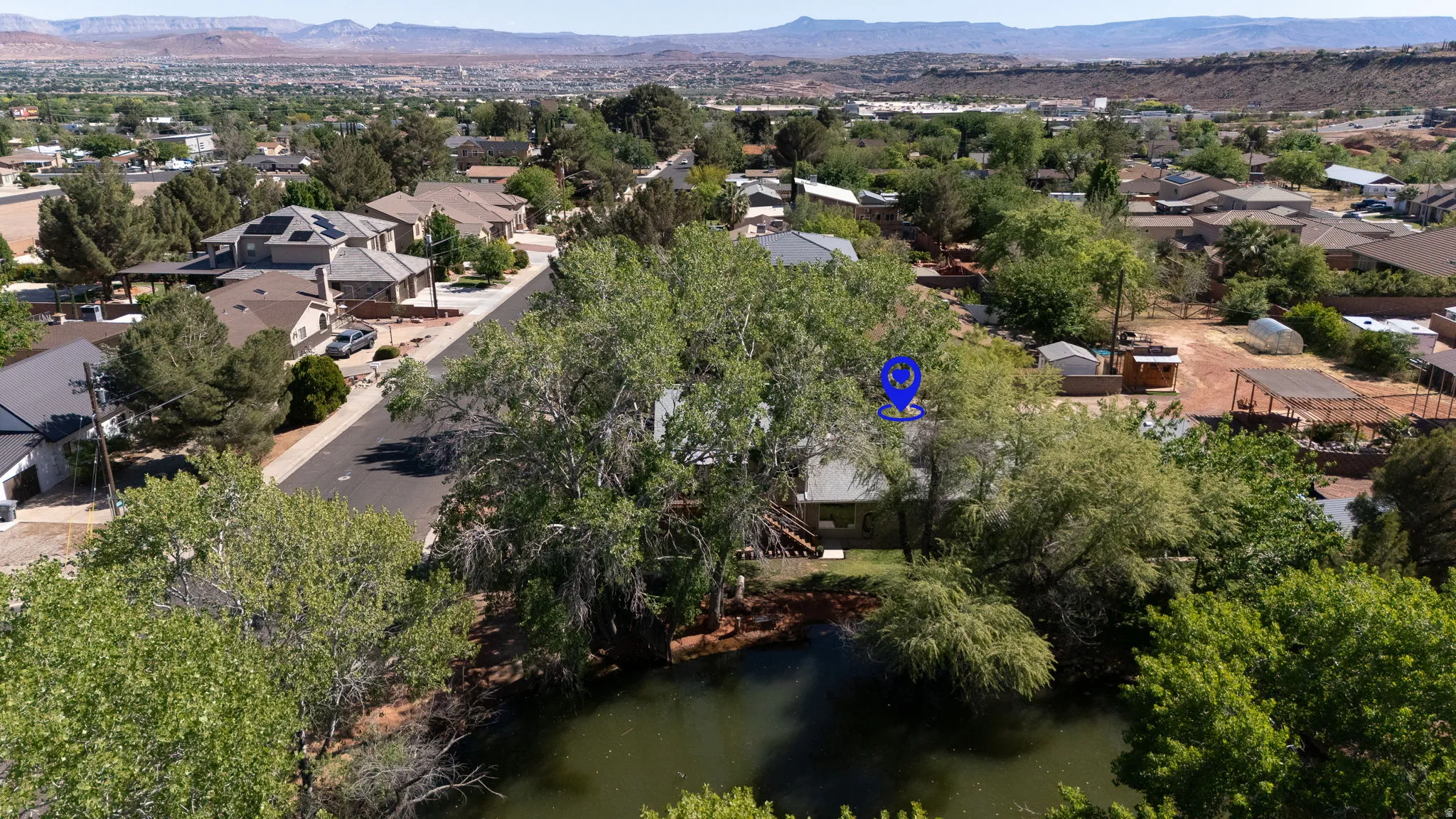 Residential property with mature trees, surrounded by additional residences and distant mountains