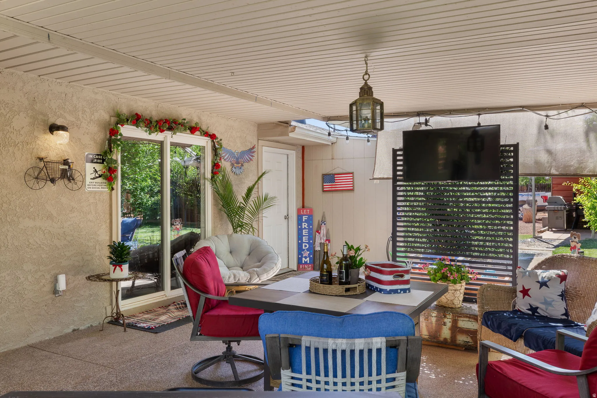 Covered patio space featuring a textured concrete floor, exterior wall lighting fixture, and a sliding glass door