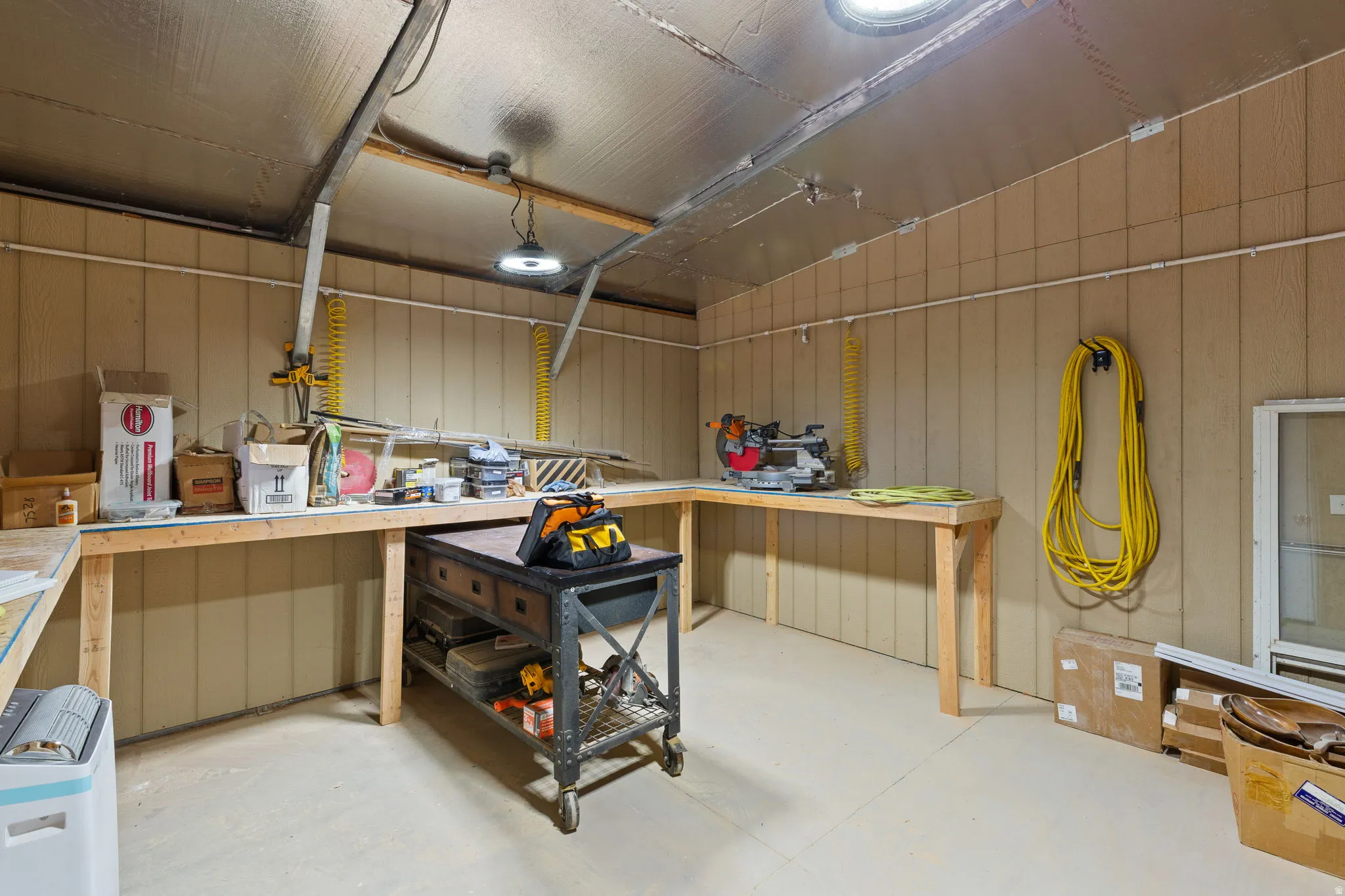 Workshop featuring extensive workbench space, panel walls, overhead lighting, and two circular skylights