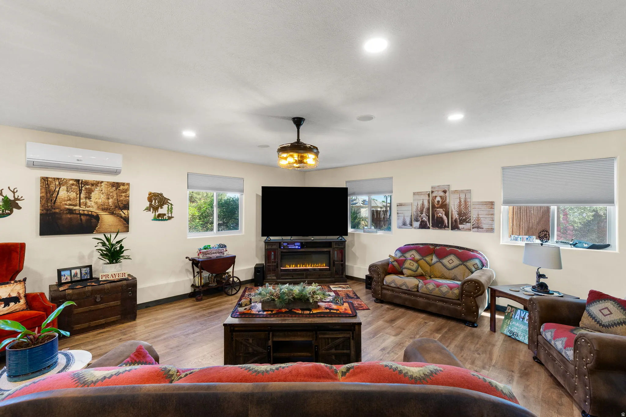Spacious living area featuring wood-finish flooring, recessed lighting, and multiple windows with roller shades