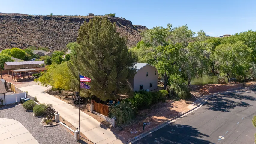 Neutral-toned exterior with a gable roofline, set amidst mature trees and natural desert landscaping