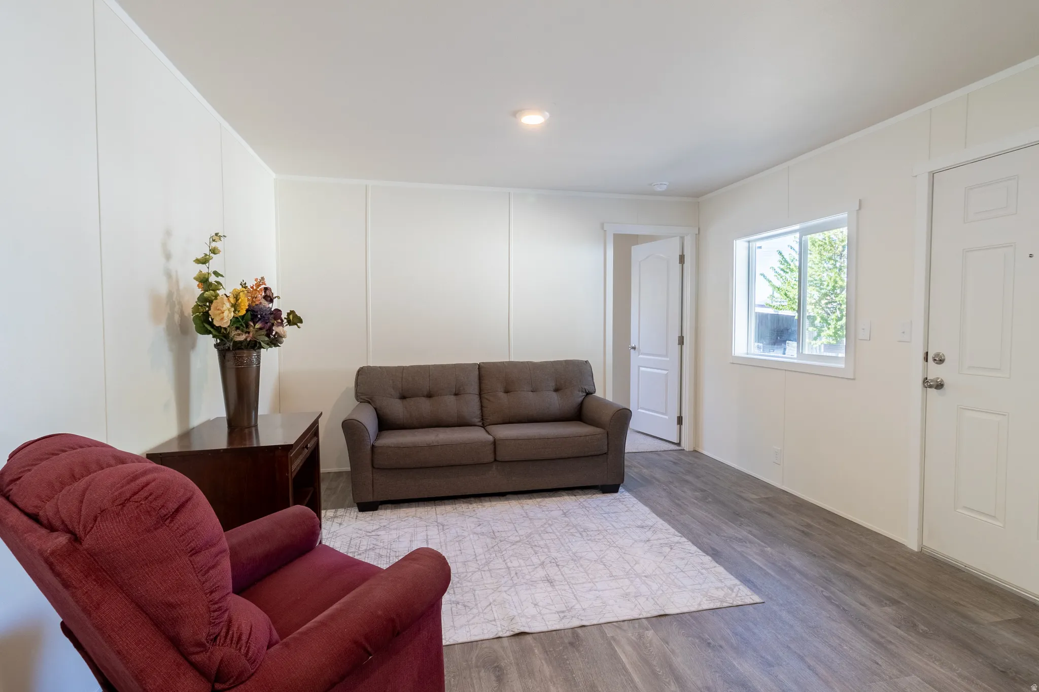 Living area featuring a decorative wall, wood finished floors, and ornamental molding