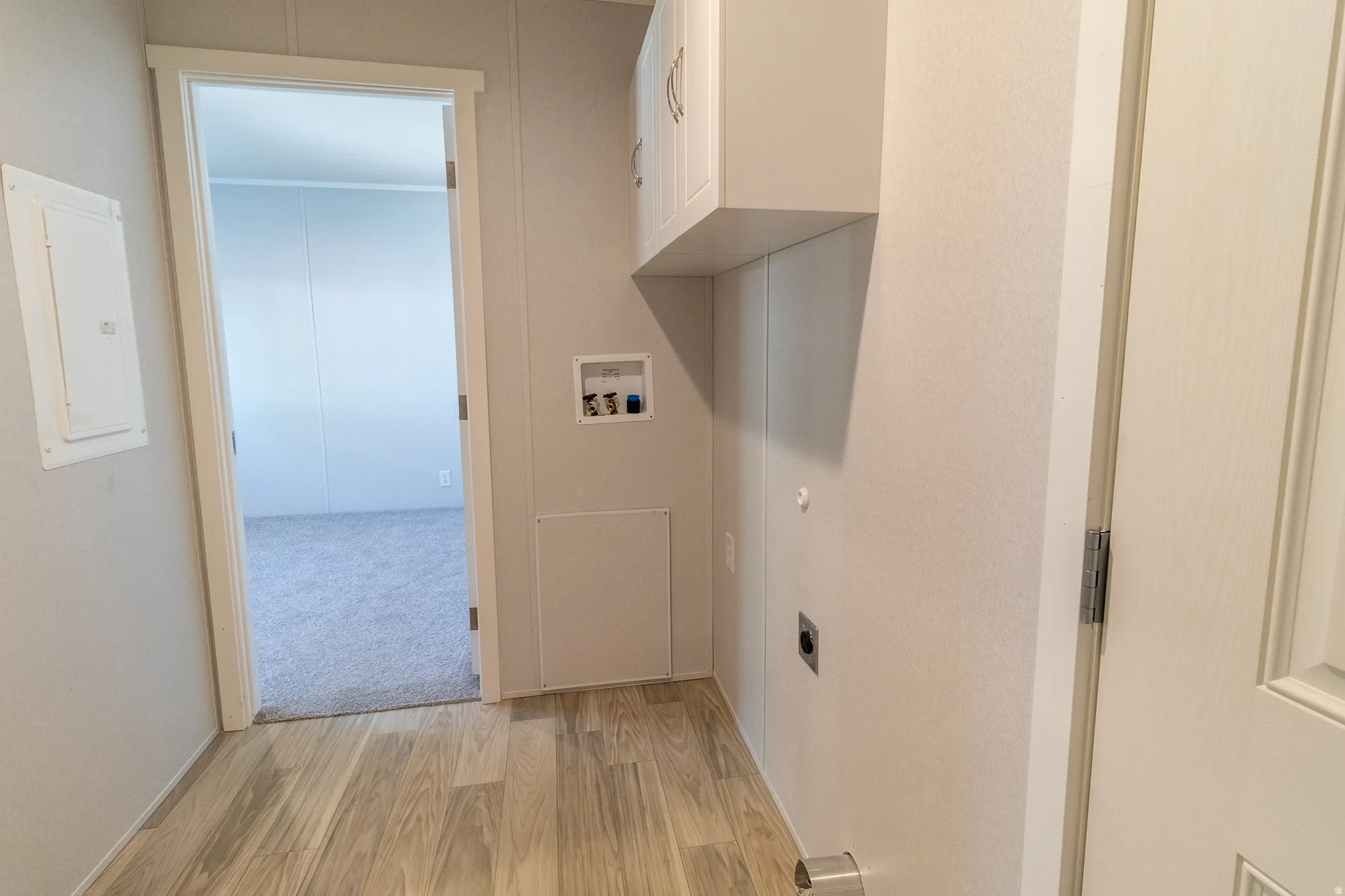 Utility area featuring wood-finish flooring, overhead cabinetry, and laundry hookups