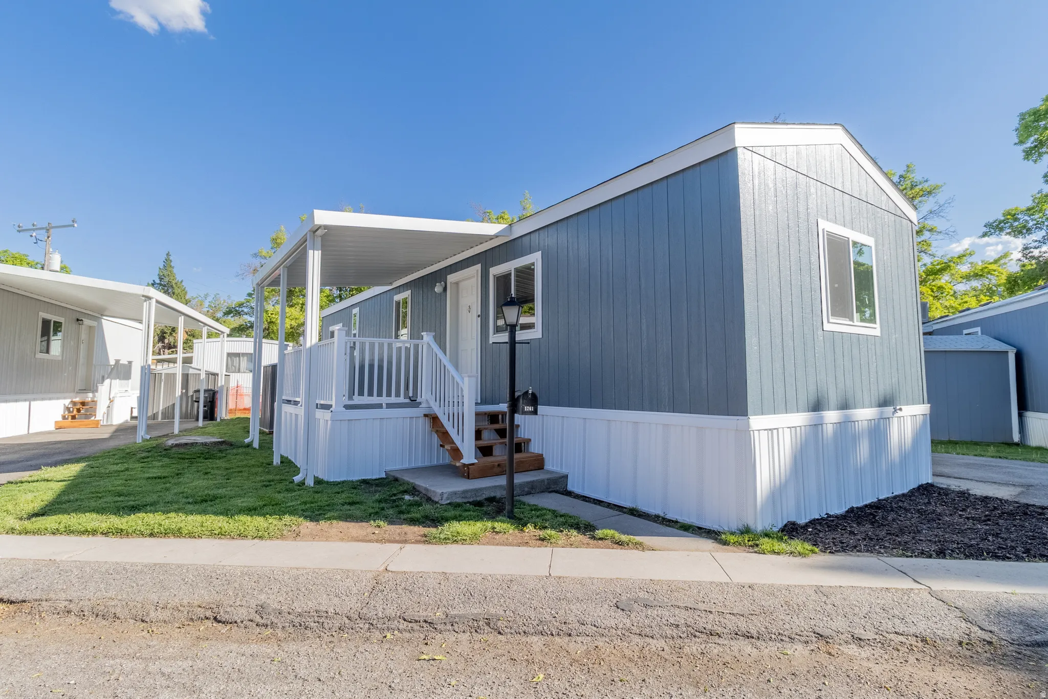 Modern manufactured home with blue siding, white trim, and a covered porch entry