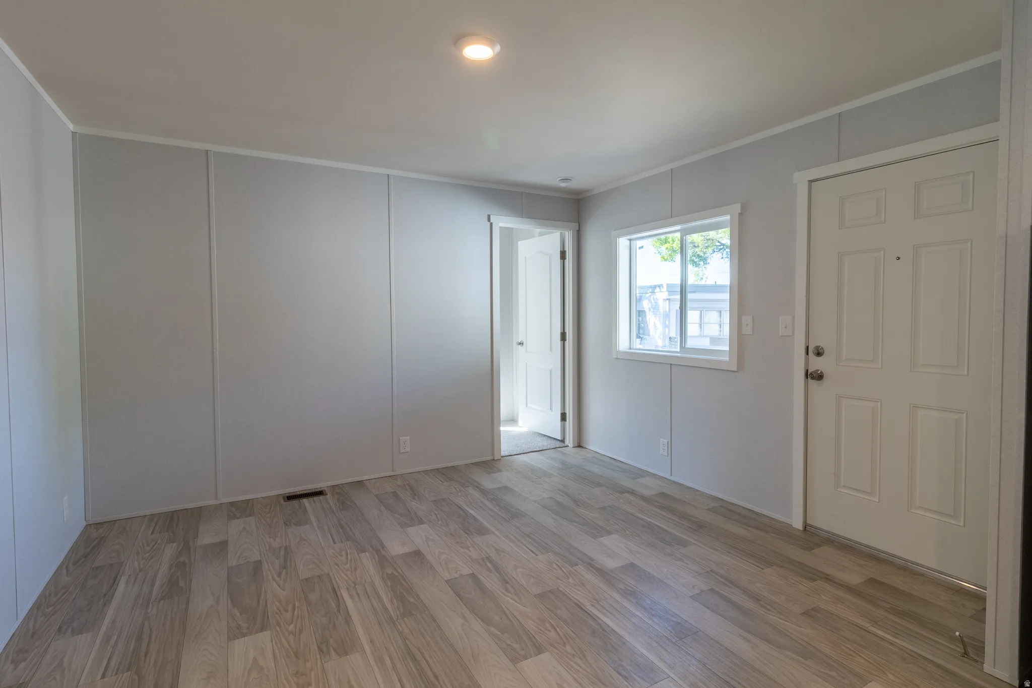 Bright interior space featuring wood-finish flooring, light gray paneled walls, and white trim