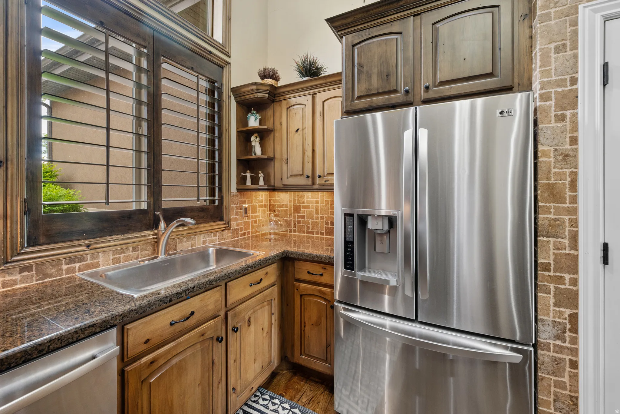 Kitchen area featuring stainless steel French door refrigerator, undermount sink with gooseneck faucet, granite countertops, and wood cabinetry