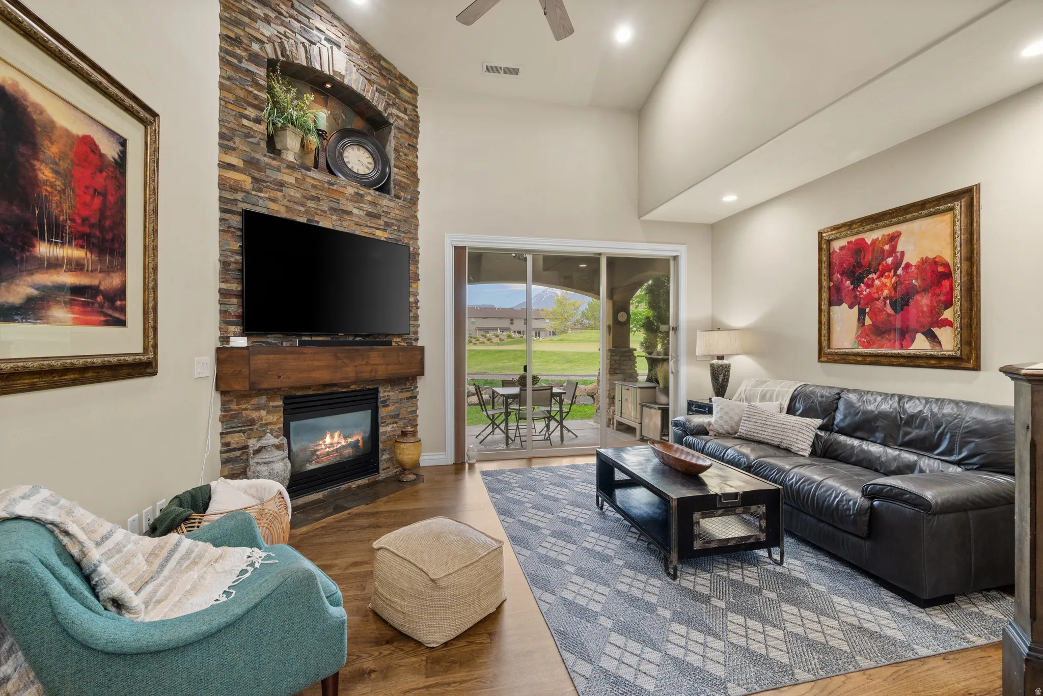 Living space featuring a stacked stone fireplace with a substantial wood mantle, vaulted ceilings, recessed lighting, and wood-finish flooring