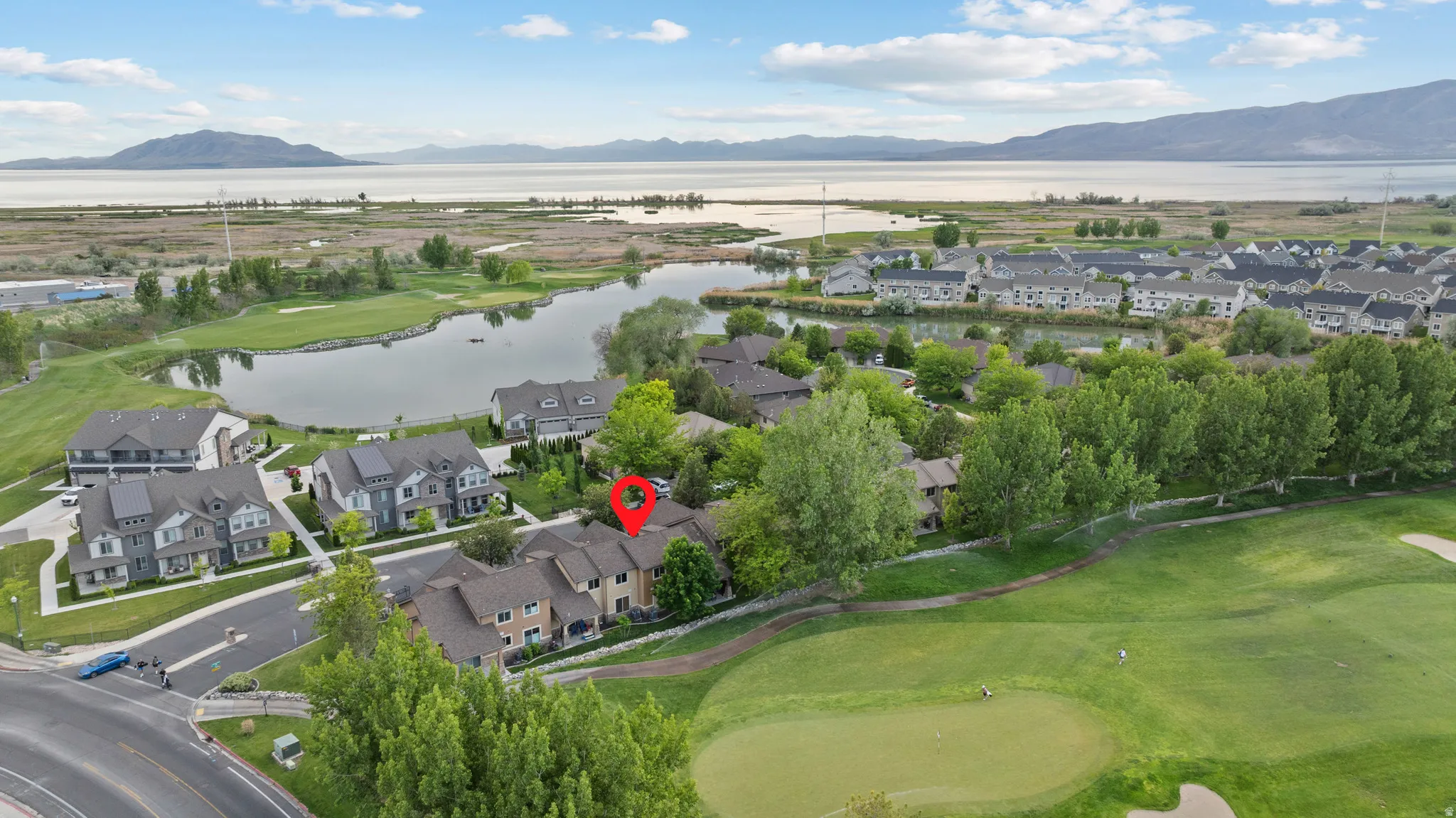 Townhome community situated alongside a golf course, featuring a lake and mountain backdrop
