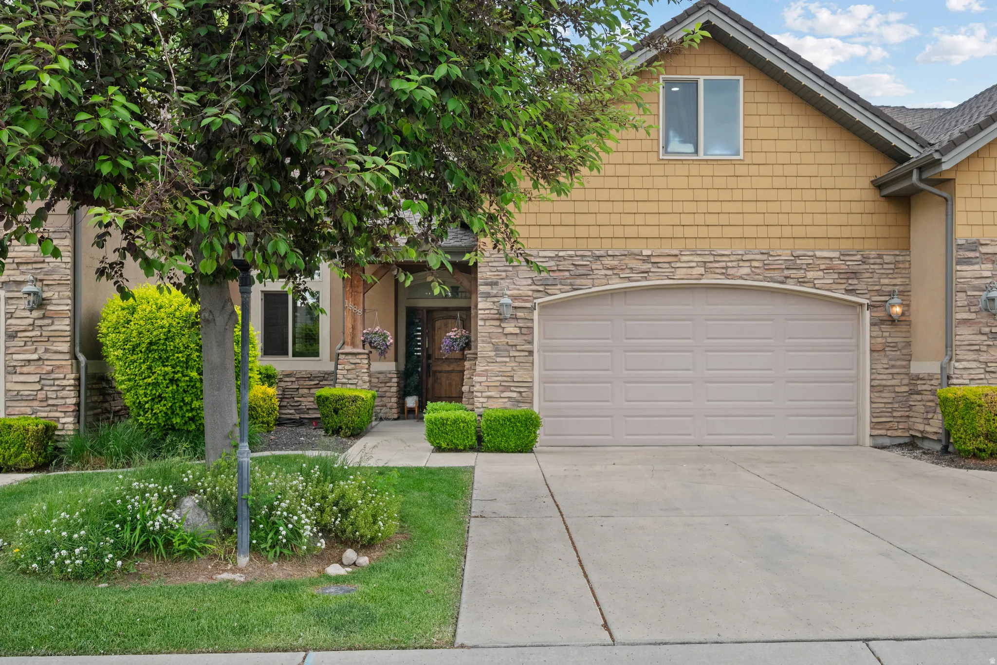 Exterior featuring a two-car garage with an arched header, stone veneer accents, and shake siding