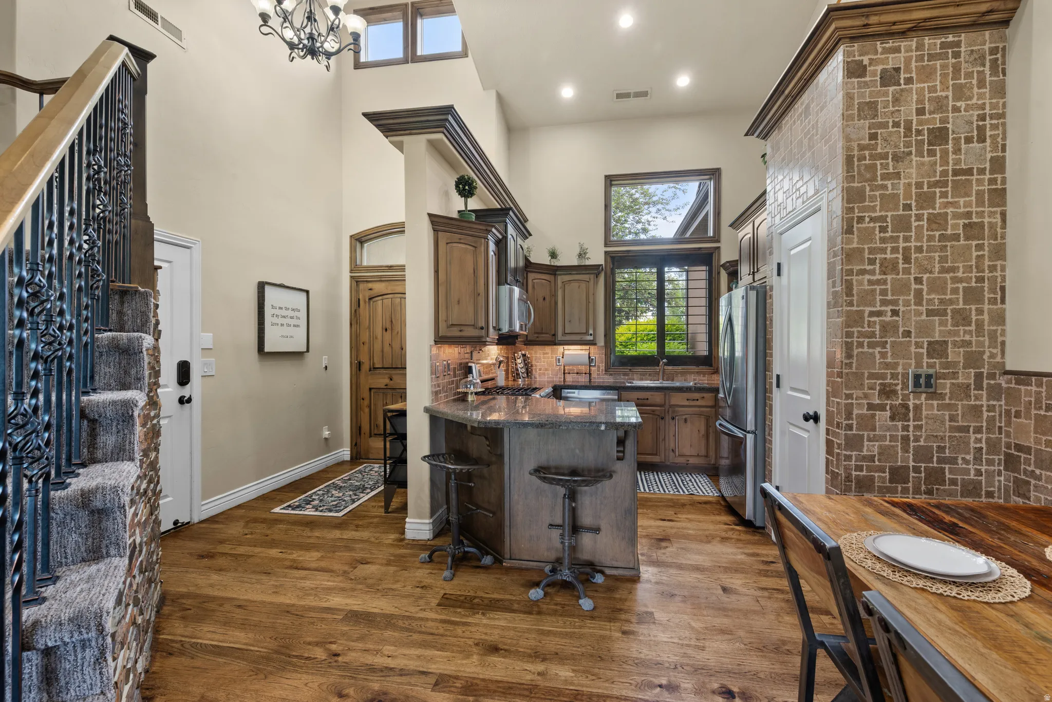 Kitchen featuring wood-finish flooring, custom wood cabinetry, and a granite island with seating