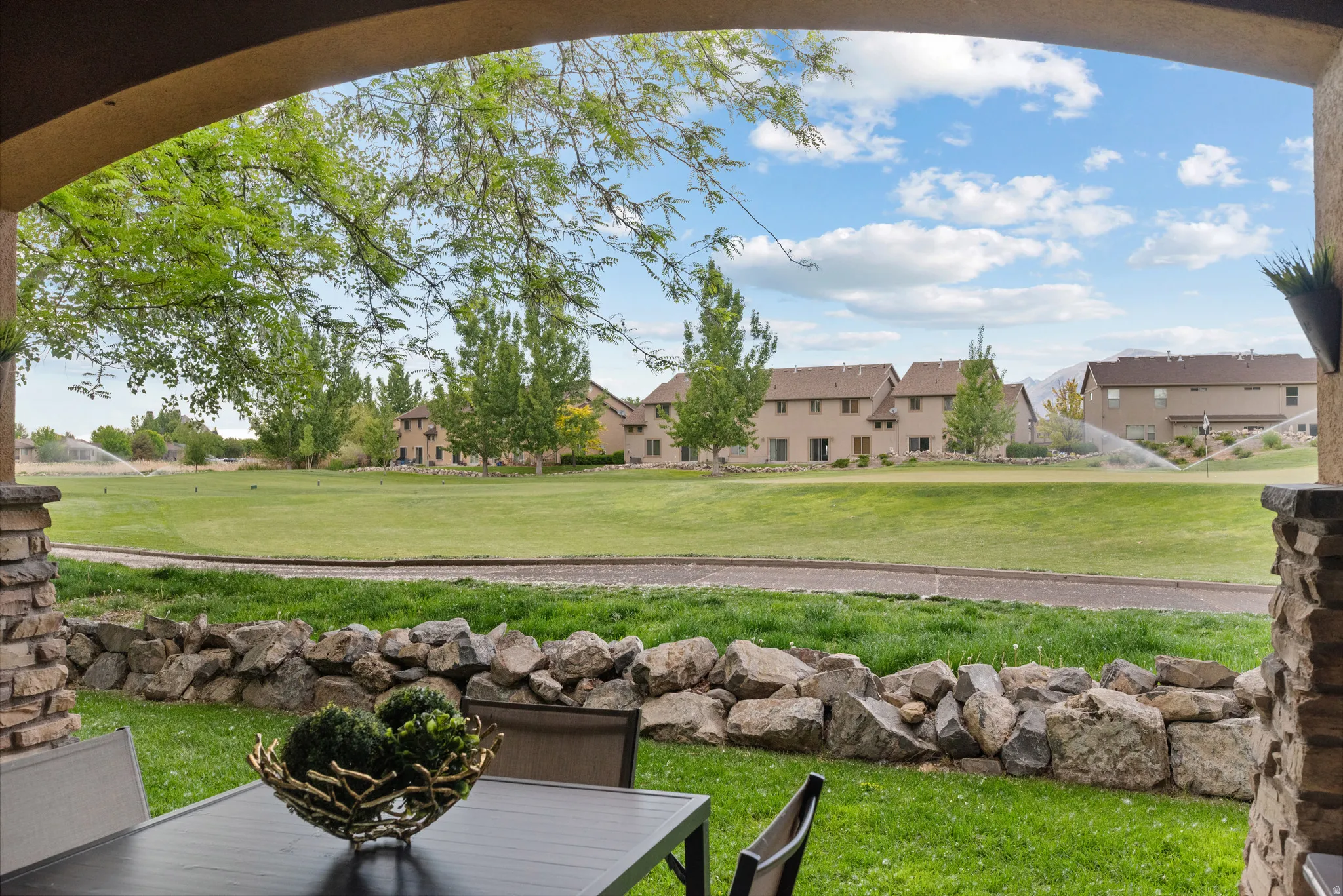 Covered patio with stacked stone pillars and arched ceiling overlooking a lush green golf course.