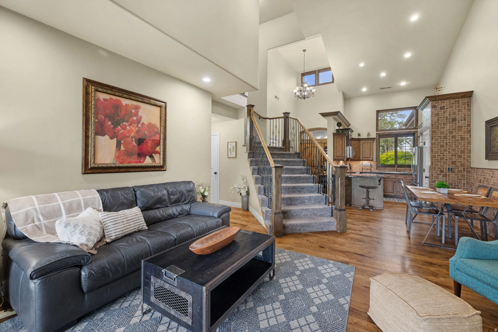 Two-story living area featuring wood-finish flooring, a grand staircase with wood newel posts, and recessed lighting