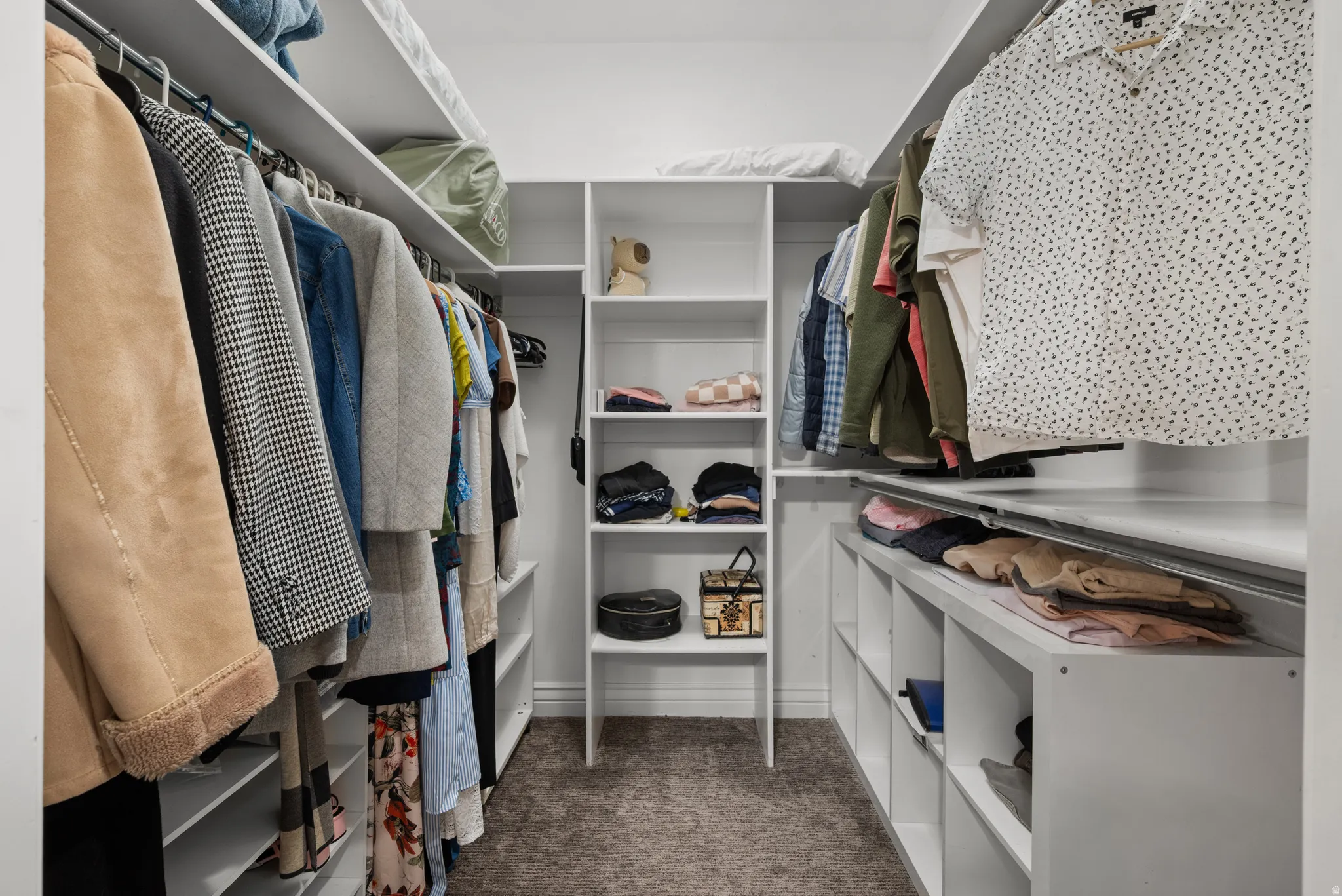 Walk-in closet for principle bedroom featuring built-in white shelving, hanging rods, and integrated cubbies