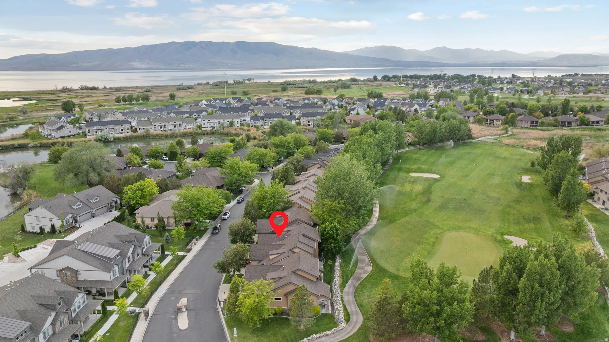 Aerial perspective showcasing a residential community with golf course proximity and distant water body