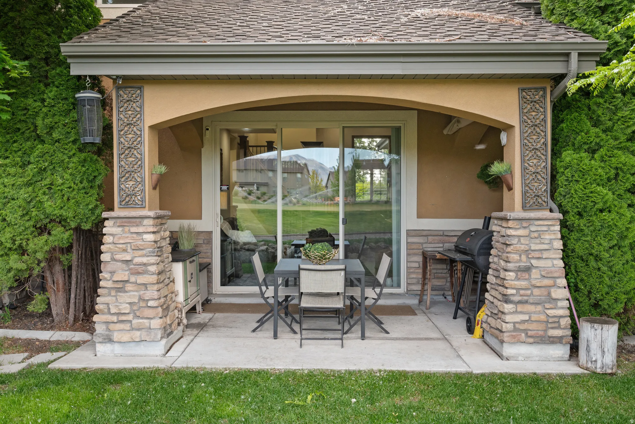 Covered patio featuring an arched stucco ceiling, stone-clad columns, and direct access through a sliding glass door