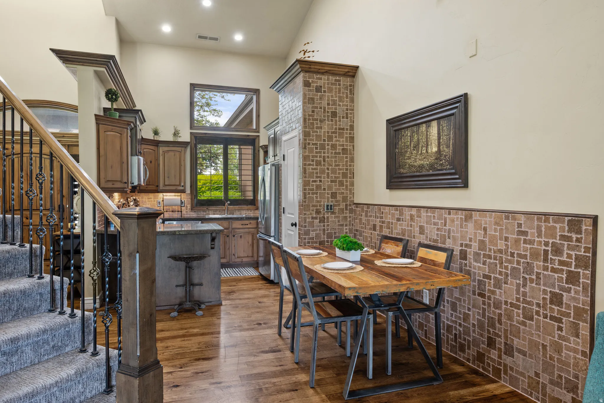 Dining area featuring wood-finish flooring, a mosaic tile wainscoting, and high vaulted ceilings