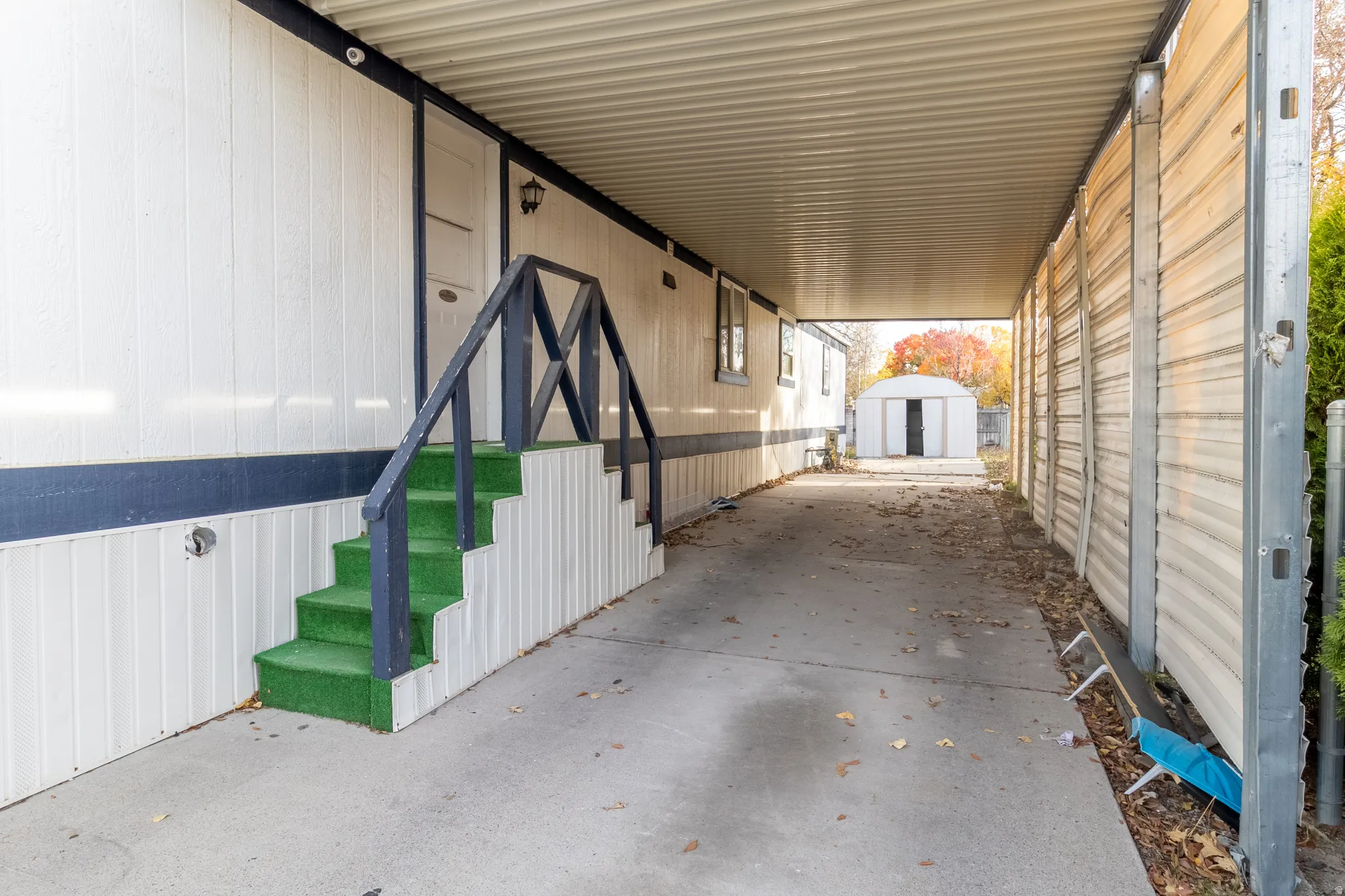 Covered carport providing sheltered parking, with direct access to the side entry
