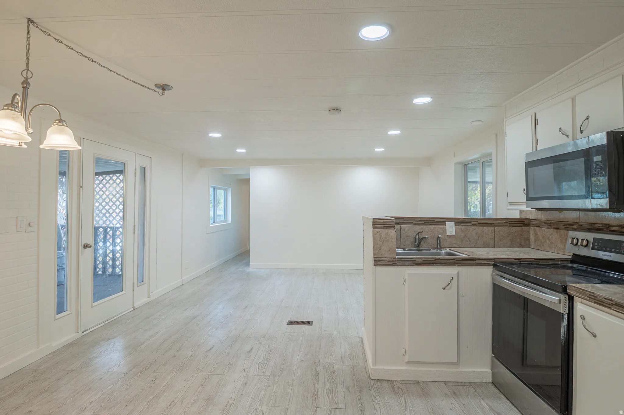 Open concept living space featuring wood-finish flooring, recessed lighting, and a modern kitchen