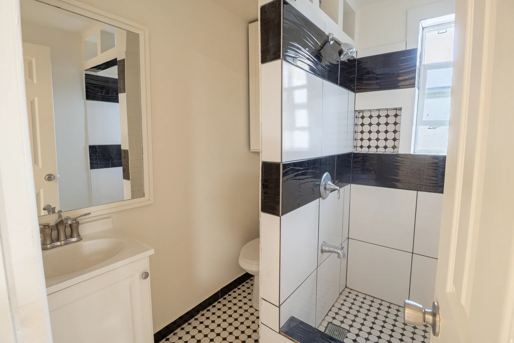 Bathroom featuring a white vanity with integrated sink, coordinating wall mirror, and a tiled shower stall