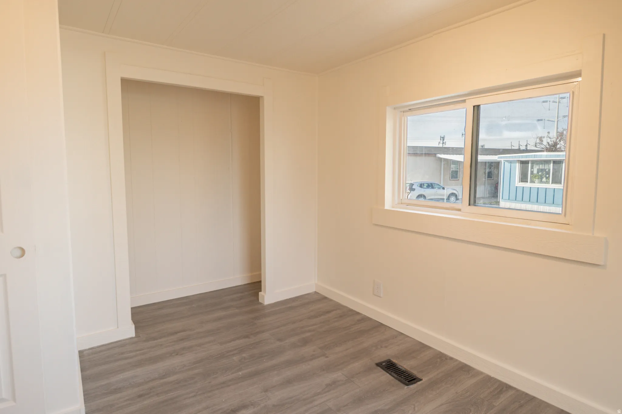 Interior room featuring wood-finish flooring, white paneled walls, and a recessed opening