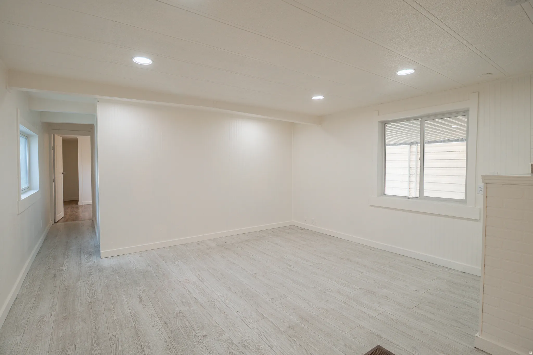 Spacious room featuring light wood-finish flooring, recessed lighting, and white baseboards