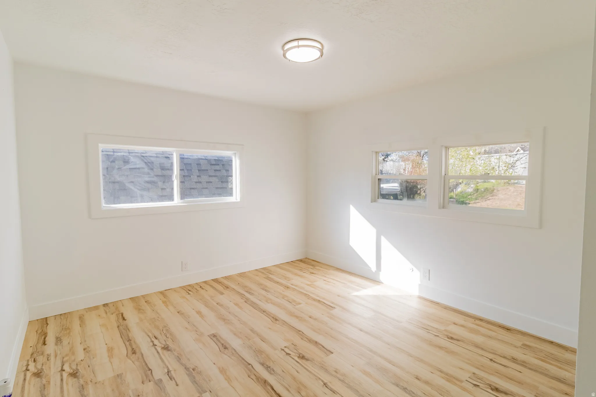 Bright room featuring wood-finish flooring, white walls, and multiple windows