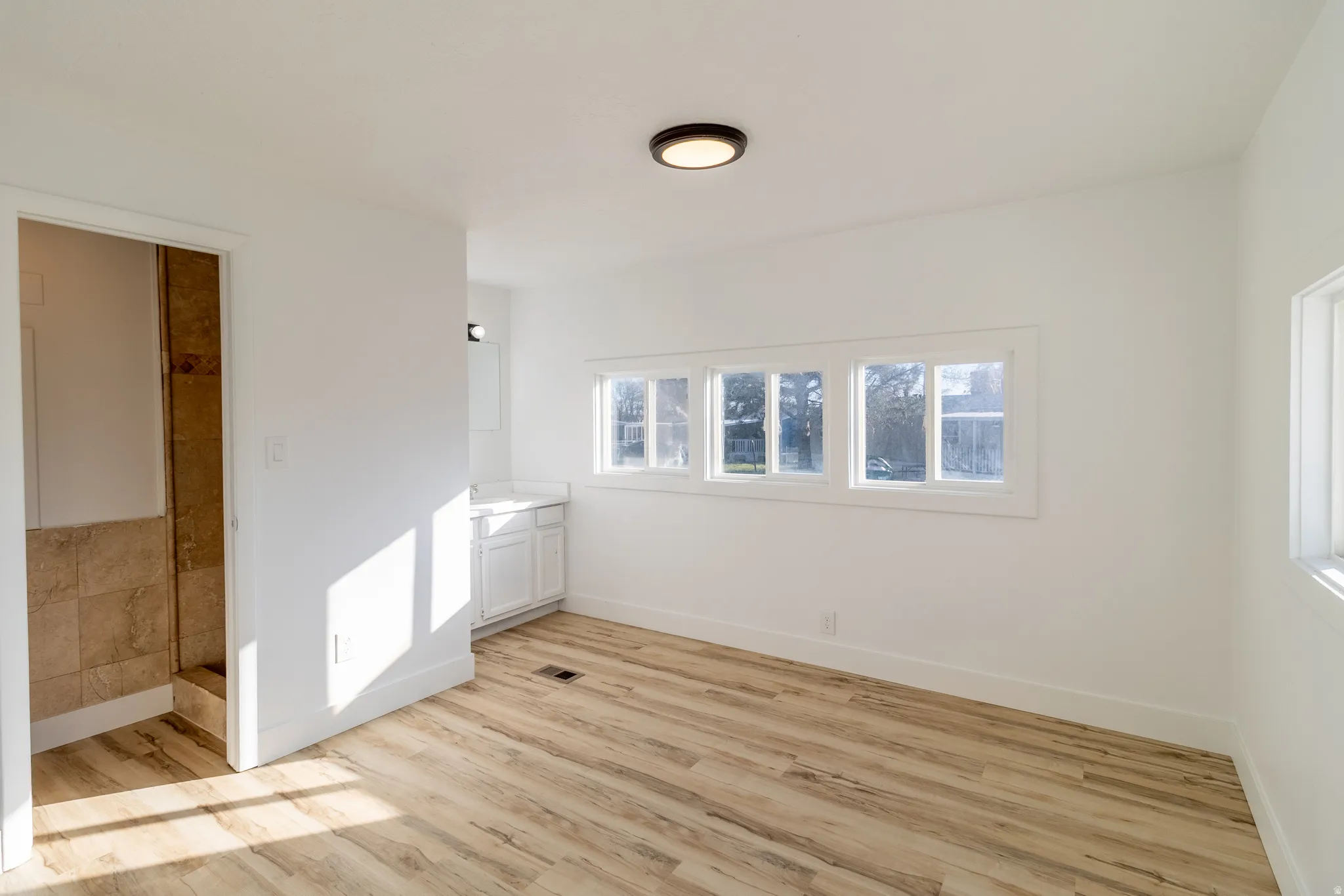 Bright interior space featuring wood-finish flooring, white walls, and a recessed ceiling light fixture