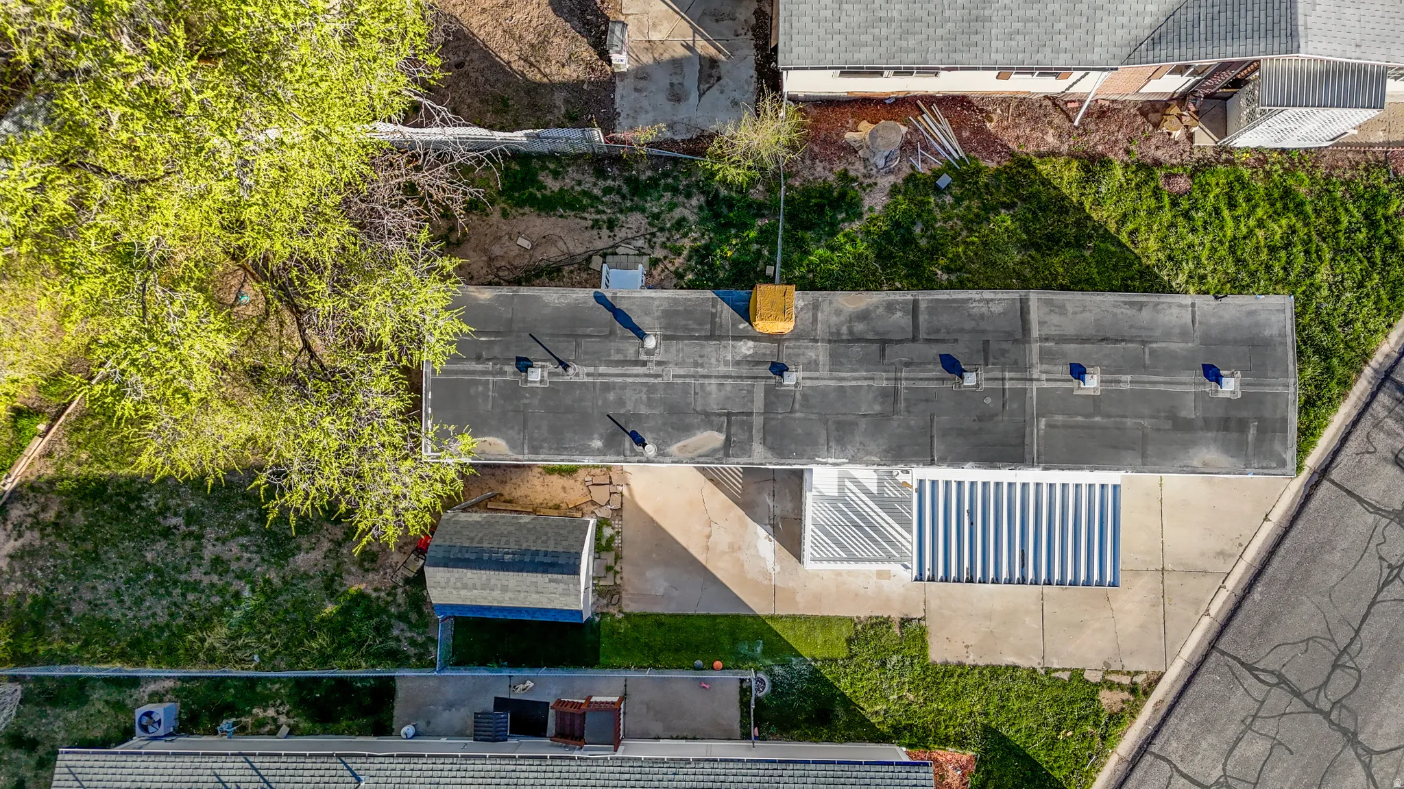 Single-story residence featuring a flat roofline, paved driveway, and a detached shed