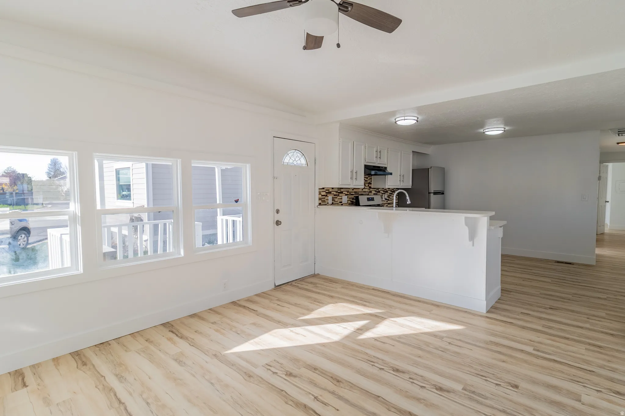 Open-concept living space featuring wood-finish flooring, white walls, and a ceiling fan