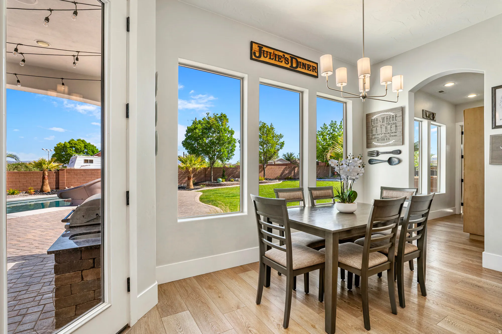 Dining area featuring three large windows, a modern chandelier, and wood-finish flooring