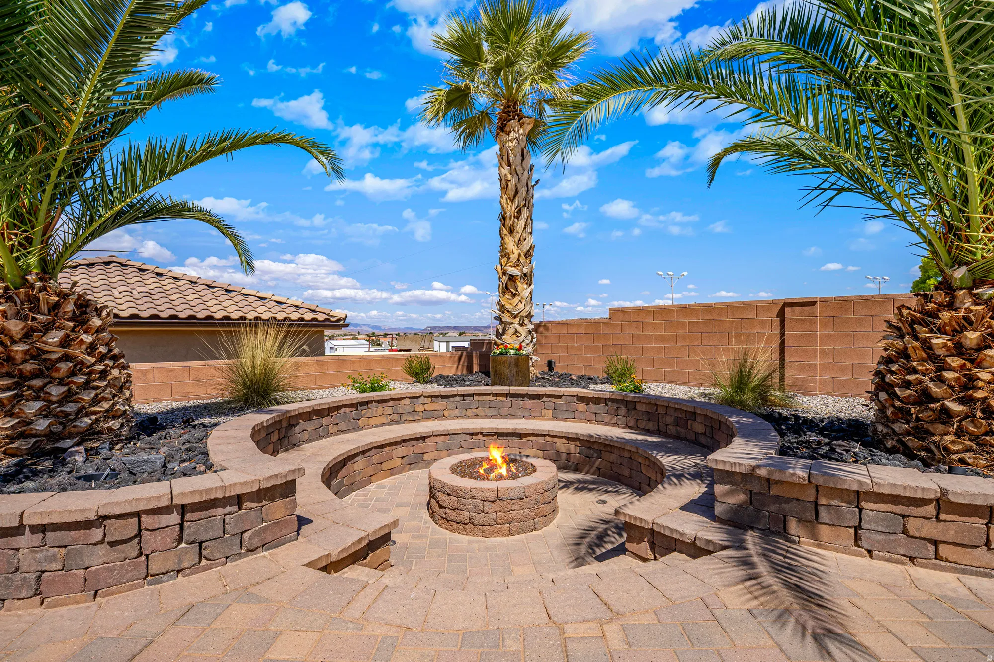 Outdoor patio featuring a built-in fire pit, tiered stone seating, and paver flooring