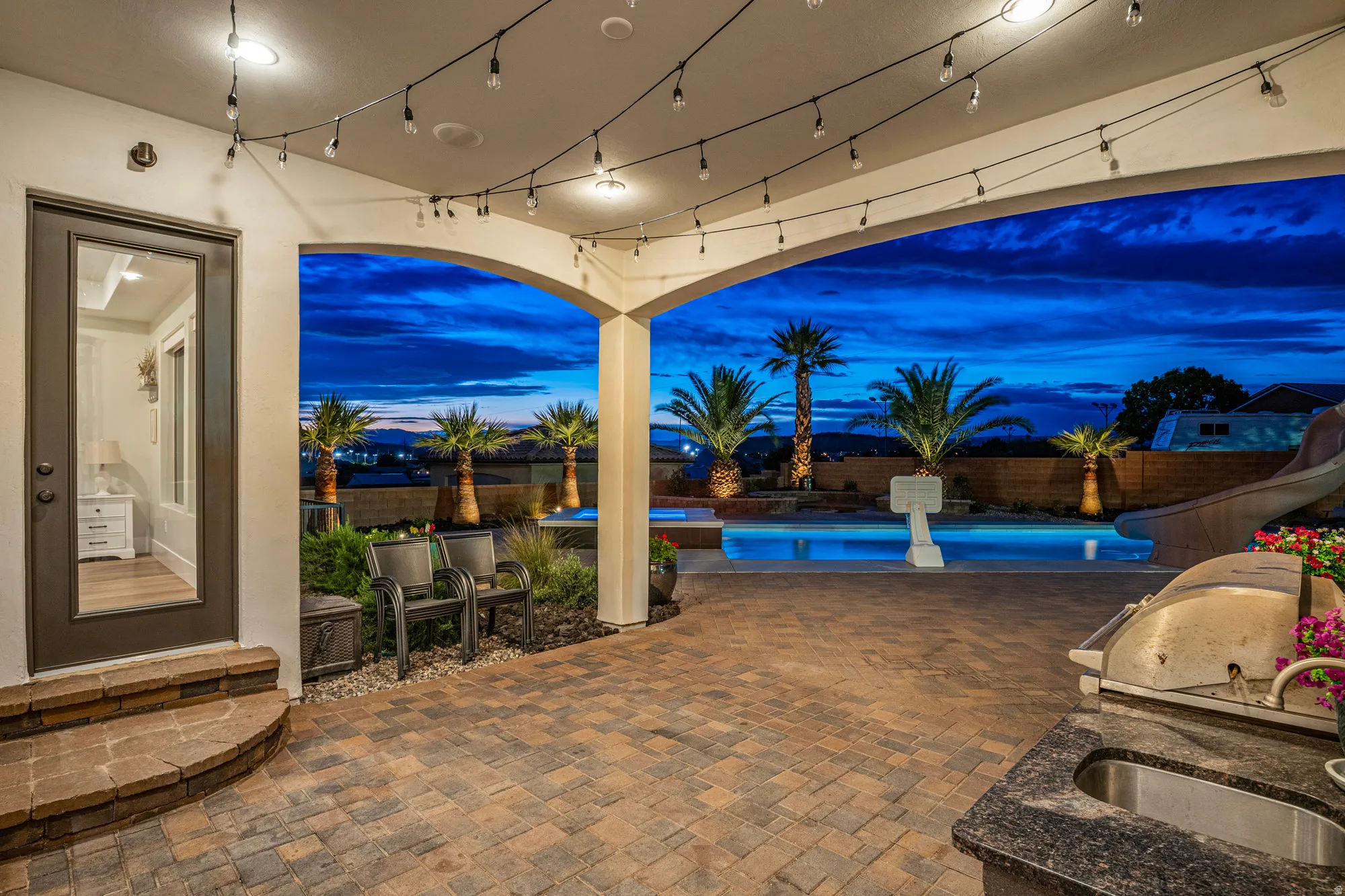 Covered patio featuring string lighting, paver flooring, and arched openings