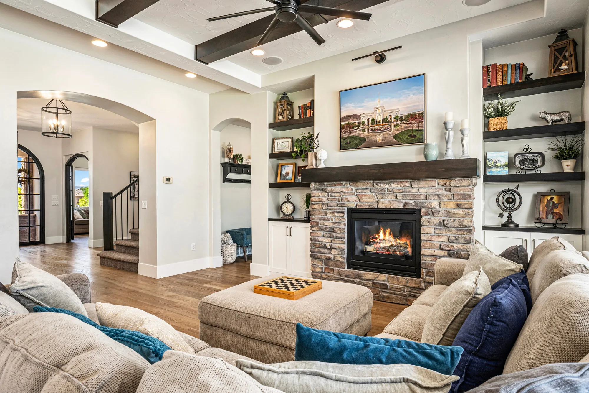 Living area featuring a stone fireplace with a wood mantle, built-in shelving, wood-finish flooring, recessed lighting, and a ceiling fan