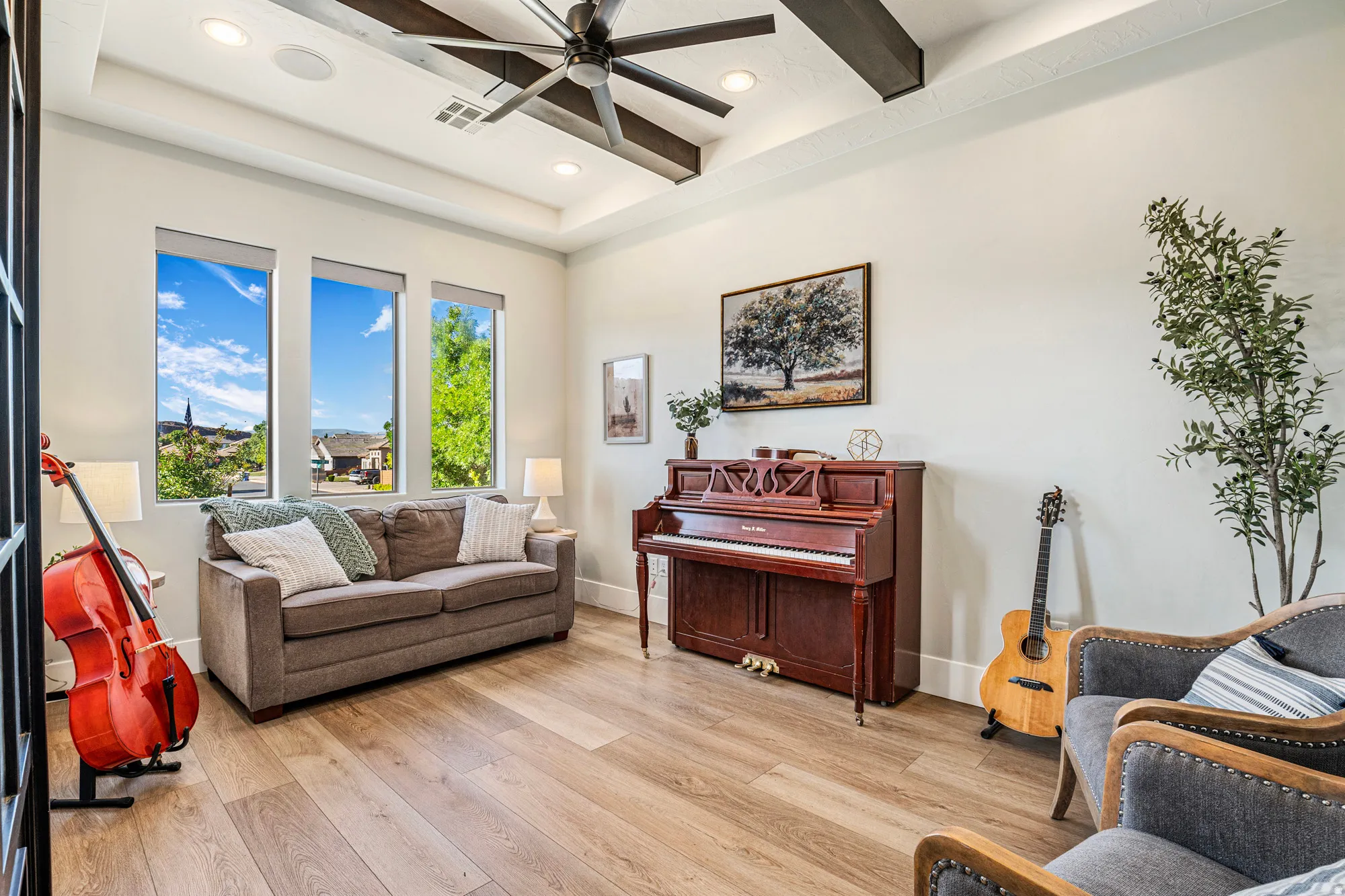 Spacious room featuring wood-finish flooring, a tray ceiling with exposed beams, and recessed lighting