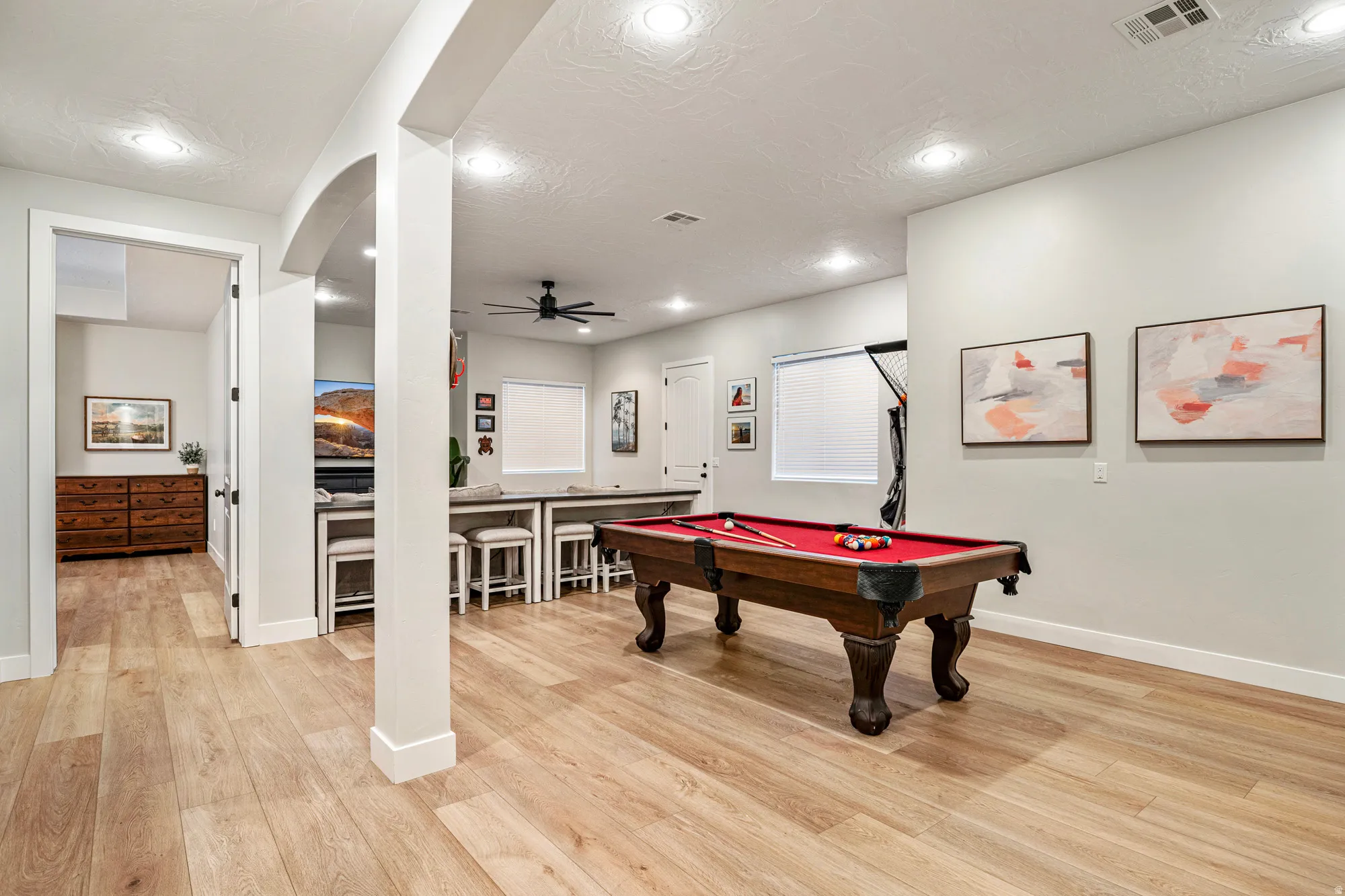 Spacious multi-purpose room featuring light wood-finish flooring, recessed lighting, and light gray walls