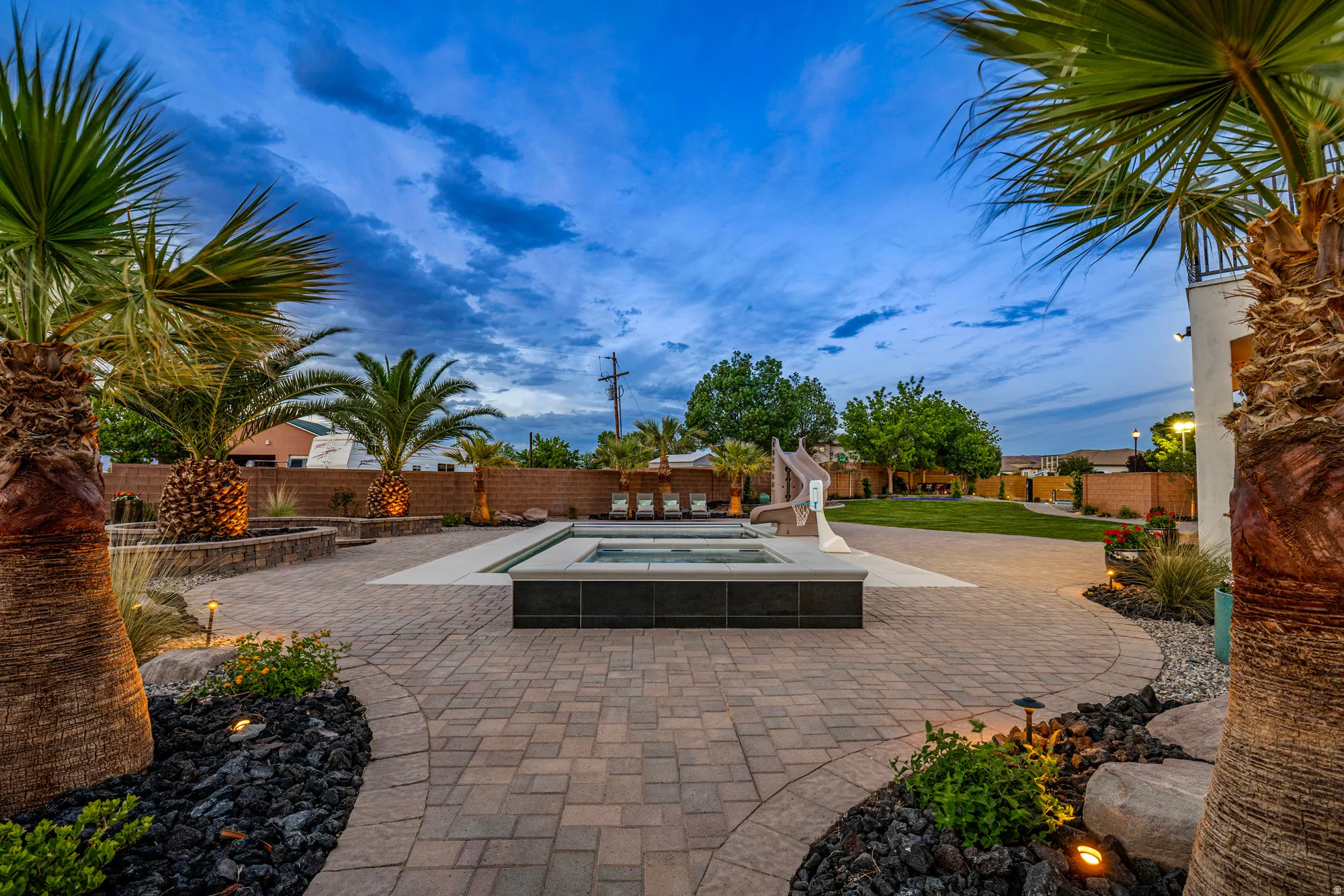 Expansive paver patio featuring an in-ground pool with integrated spa and slide