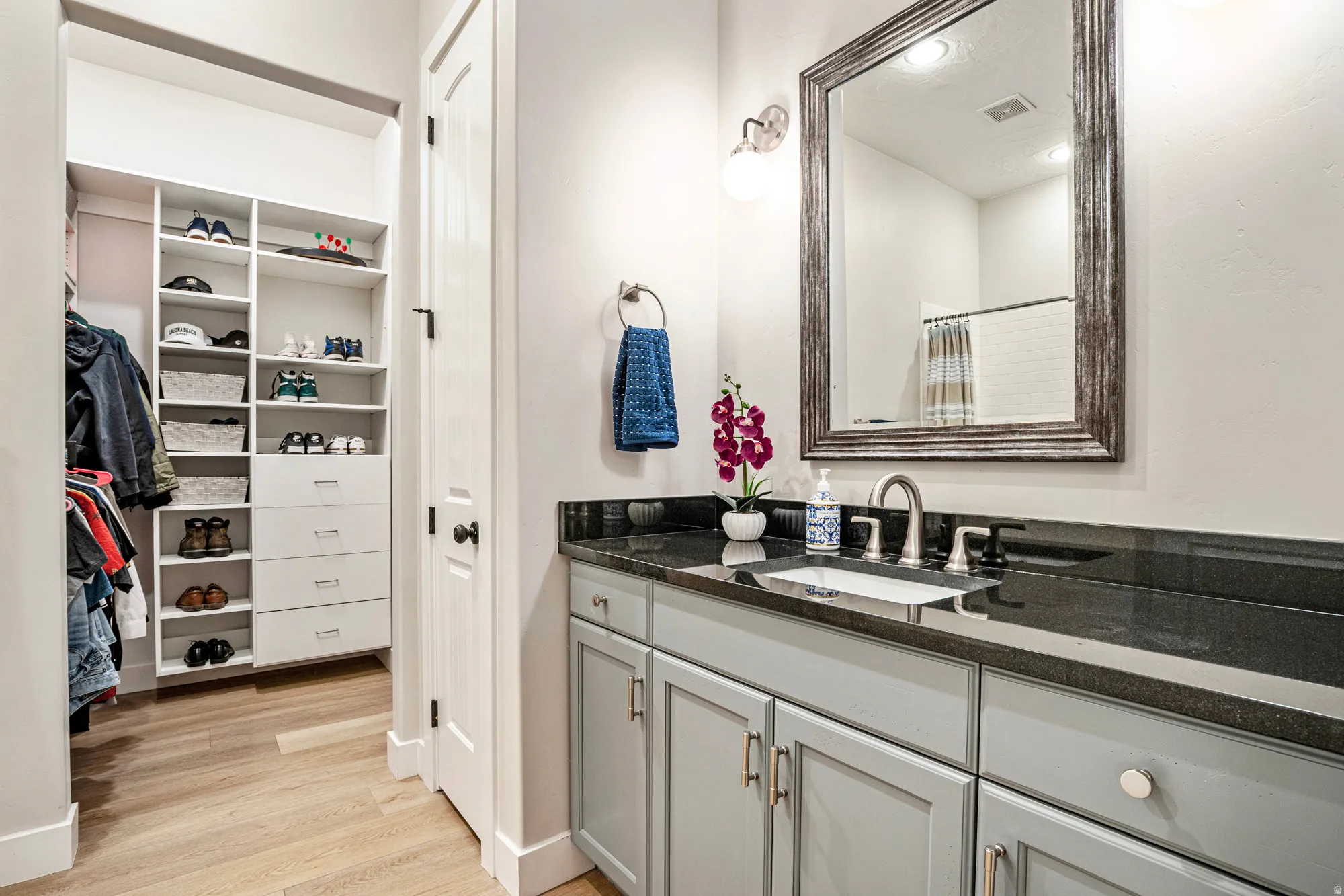 Bathroom vanity featuring a dark countertop, undermount sink, and light gray cabinetry