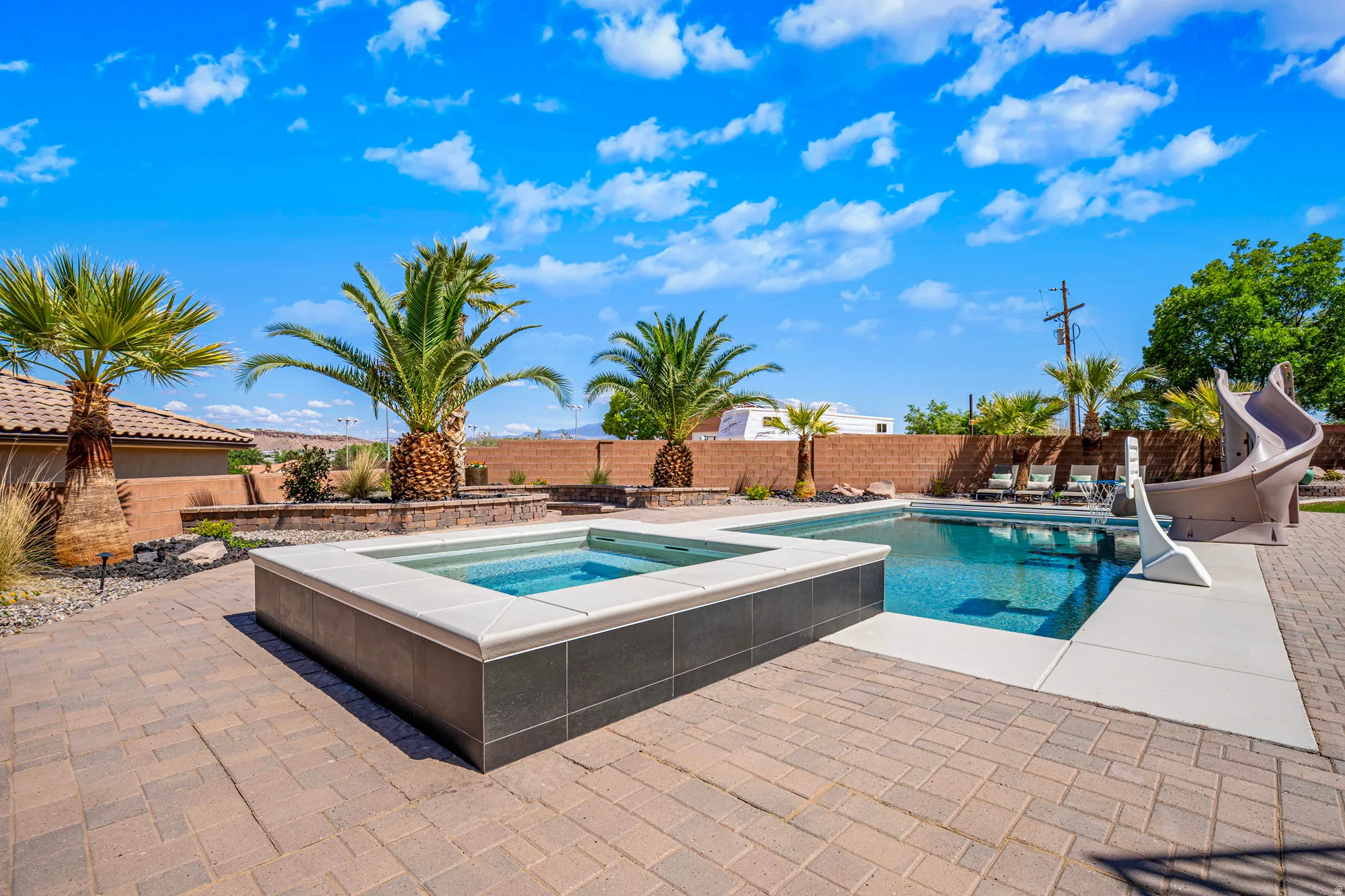 Outdoor living space featuring a swimming pool, integrated hot tub, and a decorative water slide