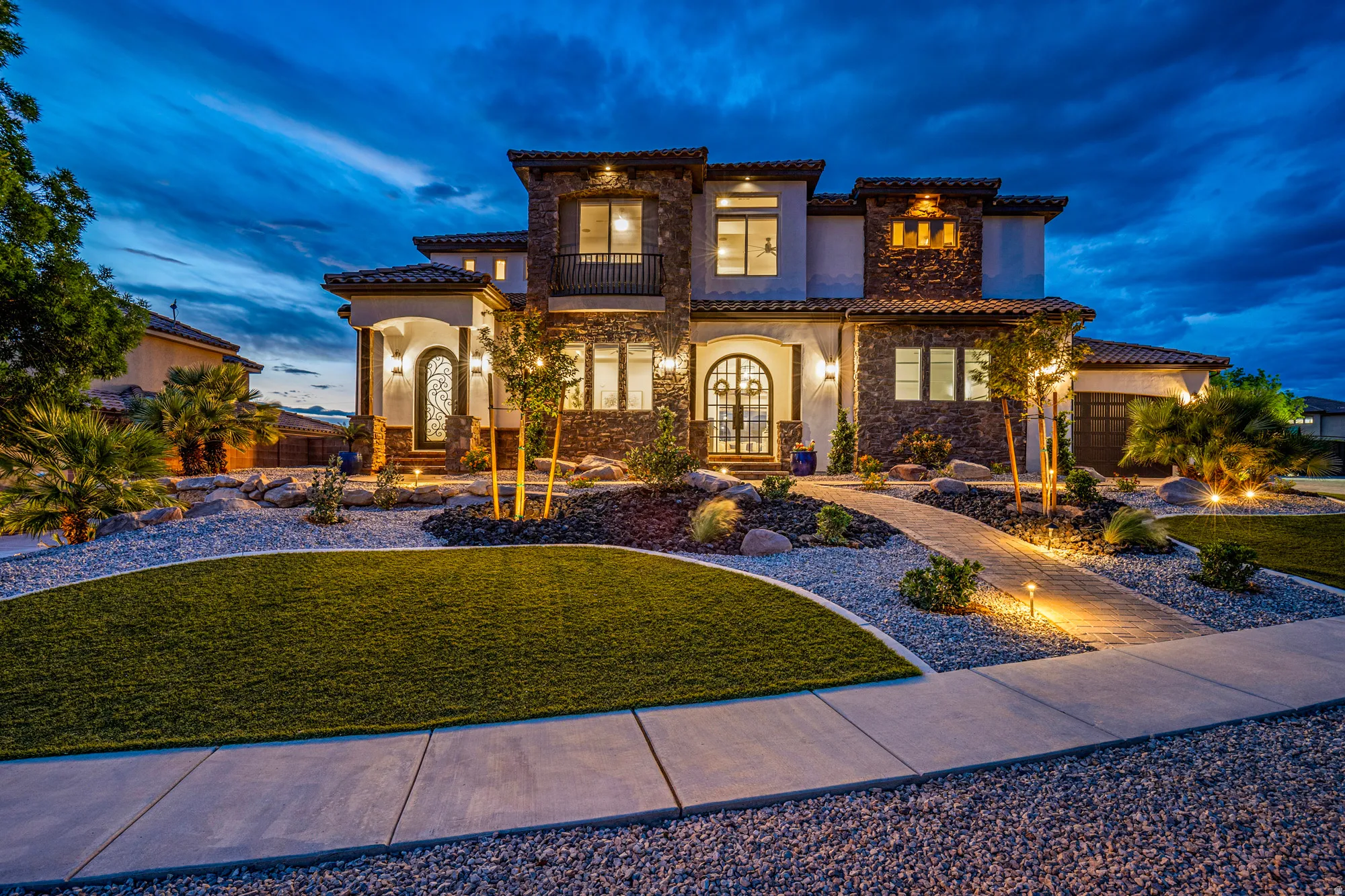 Stately two-story residence featuring a stone and stucco exterior, arched entryways, and a tile roof