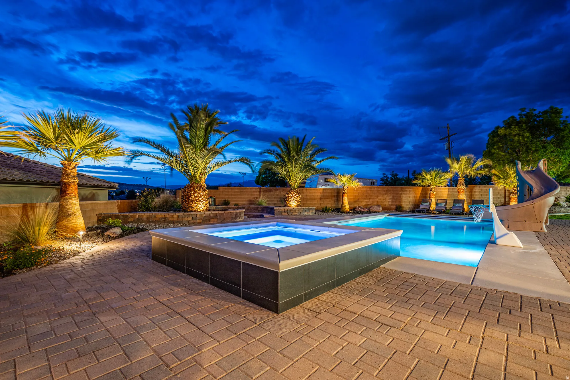 Expansive paver patio surrounding a custom swimming pool and integrated spa