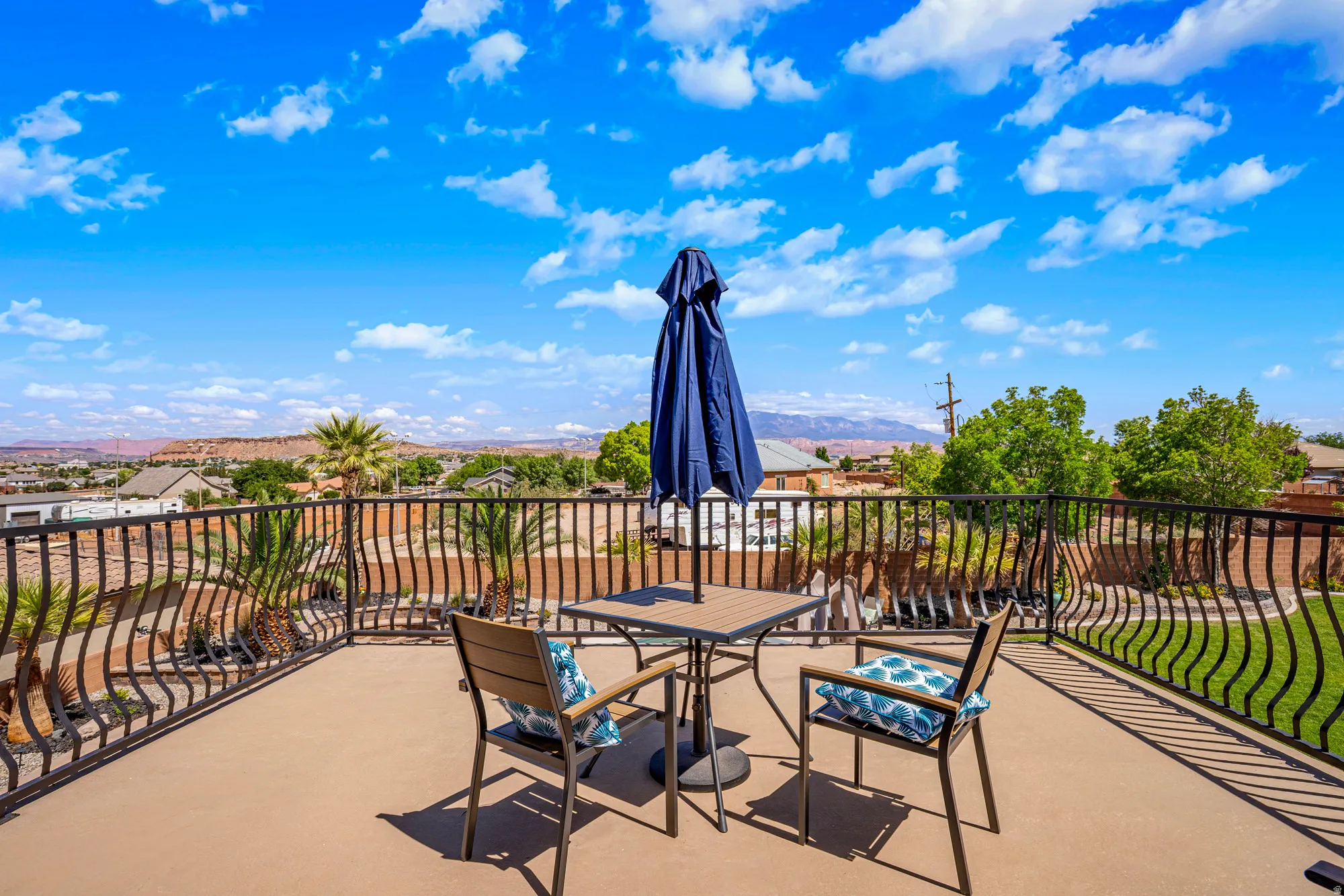 Expansive outdoor patio featuring a concrete surface, decorative metal railing, and distant mountain scenery
