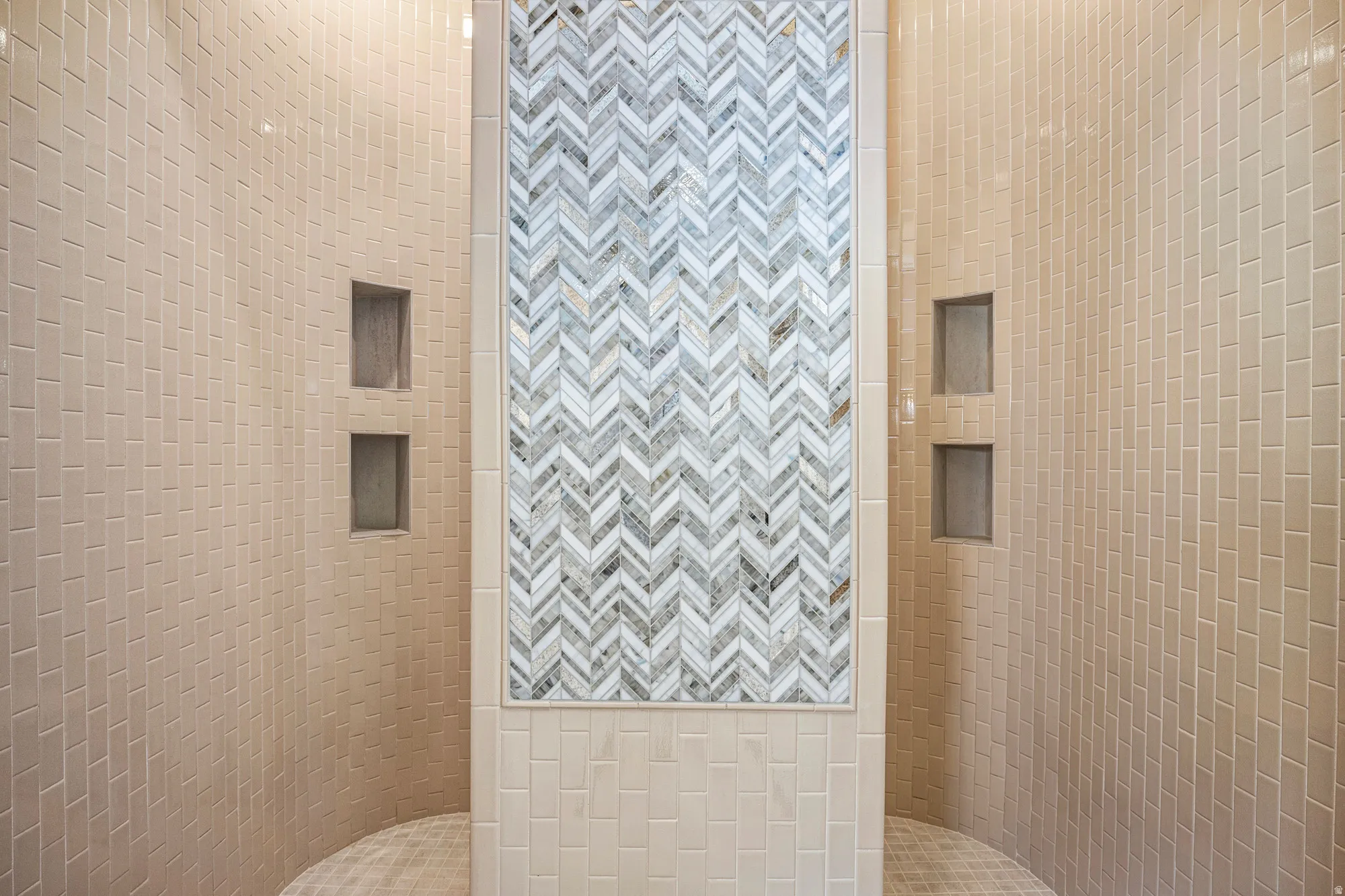 Shower enclosure featuring a herringbone mosaic tile accent wall