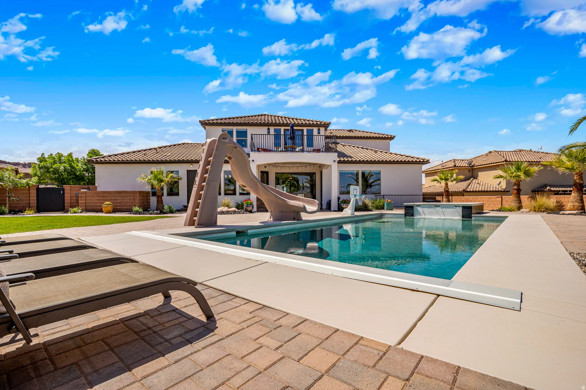 Expansive backyard featuring a rectangular swimming pool with an integrated slide and a raised water feature