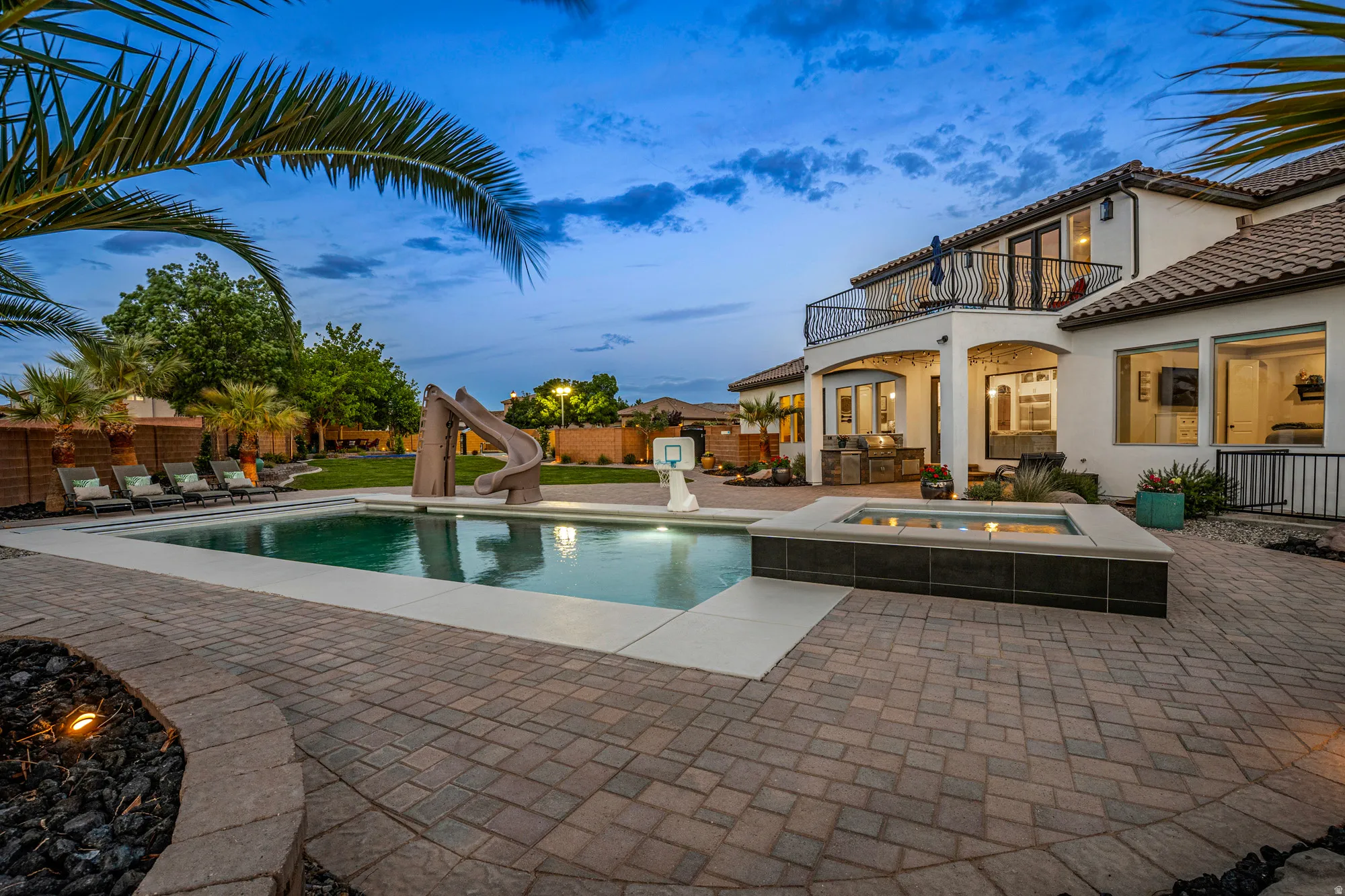 Expansive rear yard featuring a large swimming pool, integrated spa, and a multi-level patio with paver surfacing