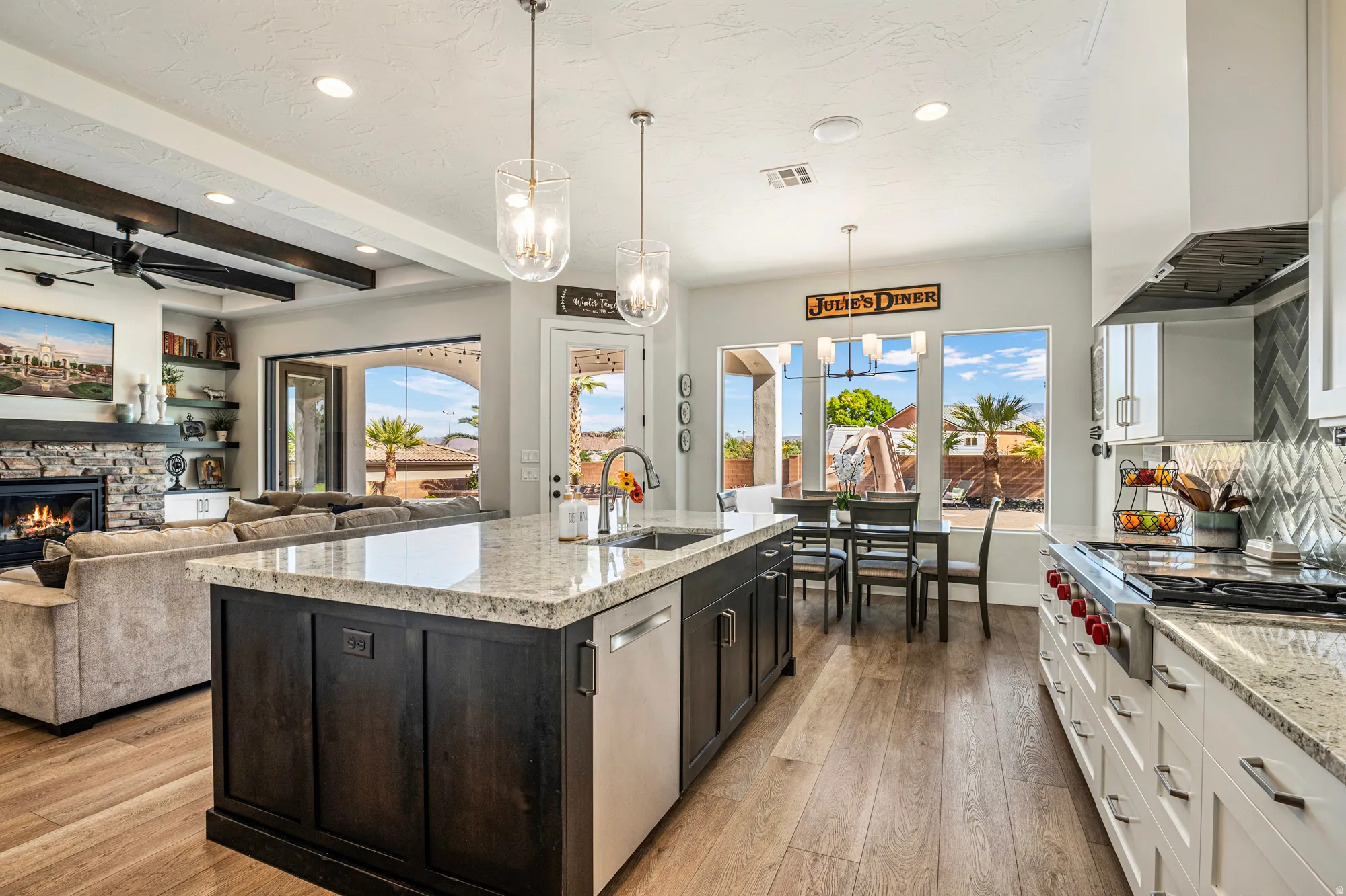 Open-concept kitchen featuring an island with a built-in sink and dishwasher, white cabinetry with a tile backsplash, and wood-finish flooring